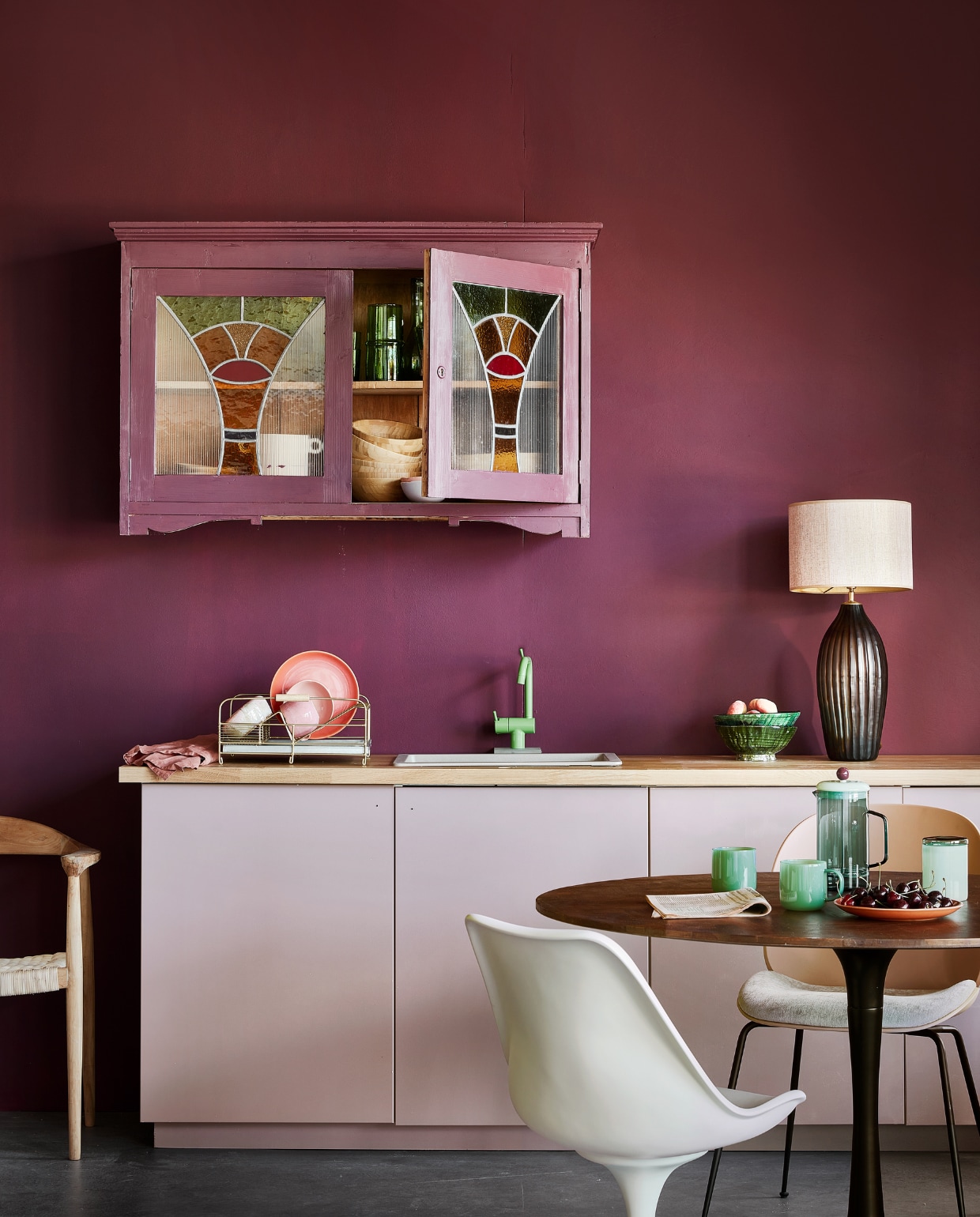 Muurverf Flexa Easycare Keuken kleur Bordeaux Leaf, per liter € 25,49, verf vintage kast Flexa Mooi Makkelijk Keukenkasten kleur Bordeaux Leaf, per 750 ml € 37,49, verf keukenkasten Flexa Mooi Makkelijk Keukenkasten kleur Heart Wood, per 750 ml  € 37,49 (Flexa). Aanrechtblad Karlby € 139,- (ikea.be). Caramelkleurige spoelbak  € 374,- (Frontz). Groene monoknop mengkraan kv1-06 € 1140,- (vola.com). Houten kast met glas in lood-deuren (marktplaats.be). Walnoothouten visgraat eettafel € 524,25, houten rattan eetkamerstoel € 171,75 (Karwei). Ivoorkleurige polyester armstoel € 629, groene schalen, 20 cm (Ø) € 29,95 (householdhardware.com). Roze eetkamerstoel van Gubi € 705,- (stockdutchdesign.com). French press € 75,-, glazen bekers, set van 2 € 59,-, opbergpot van Hay € 35,- (Drifterstore). Antiek brass afwasrek van Madam Stoltz € 65,- (Deens). Roze keramieken bord € 19,99, roze keramieken schaal € 14,99 (hm.com).  Roze handgemaakte koffiekop € 18,50 (Lilo Keramiek). Glazen tafellamp Tokyo Stripes,  € 195,-, lampenkap Catchpink € 145,- (Madame Garage). vtwonen 09-2022 | styling leonie Mooren | fotografie Peggy Janssen