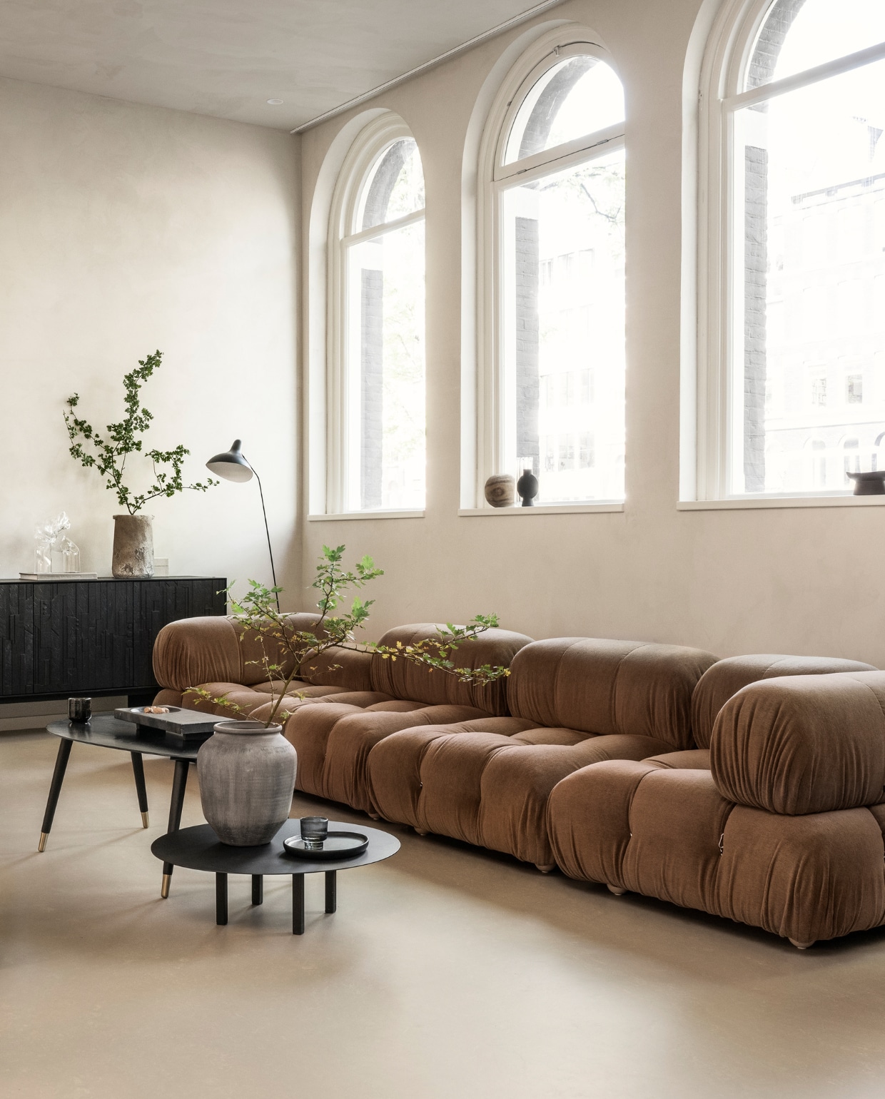 homestede.nl (elementenbank), vtwonen.nl/shop (metalen tafellamp van HKliving, ronde salontafel van Serax), ethnicraft.com (fauteuils), zarahome.com (ovale salontafel, stenen vaas, zwarte vaas, zwart houten bord), 101cph.com (stenen dienblad),  Overig privébezit. vtwonen 10-2023 | styling Sanne Ketelaar | fotografie Stan Koolen