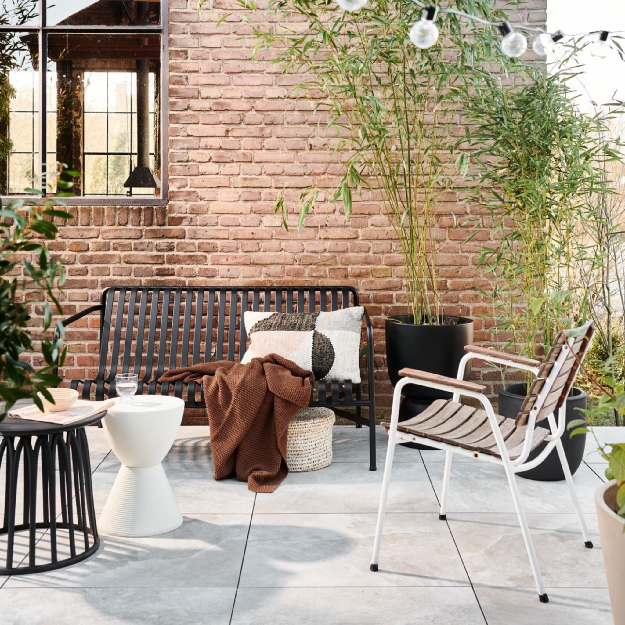 Terras met moderne buitenmeubels en hoge planten in potten