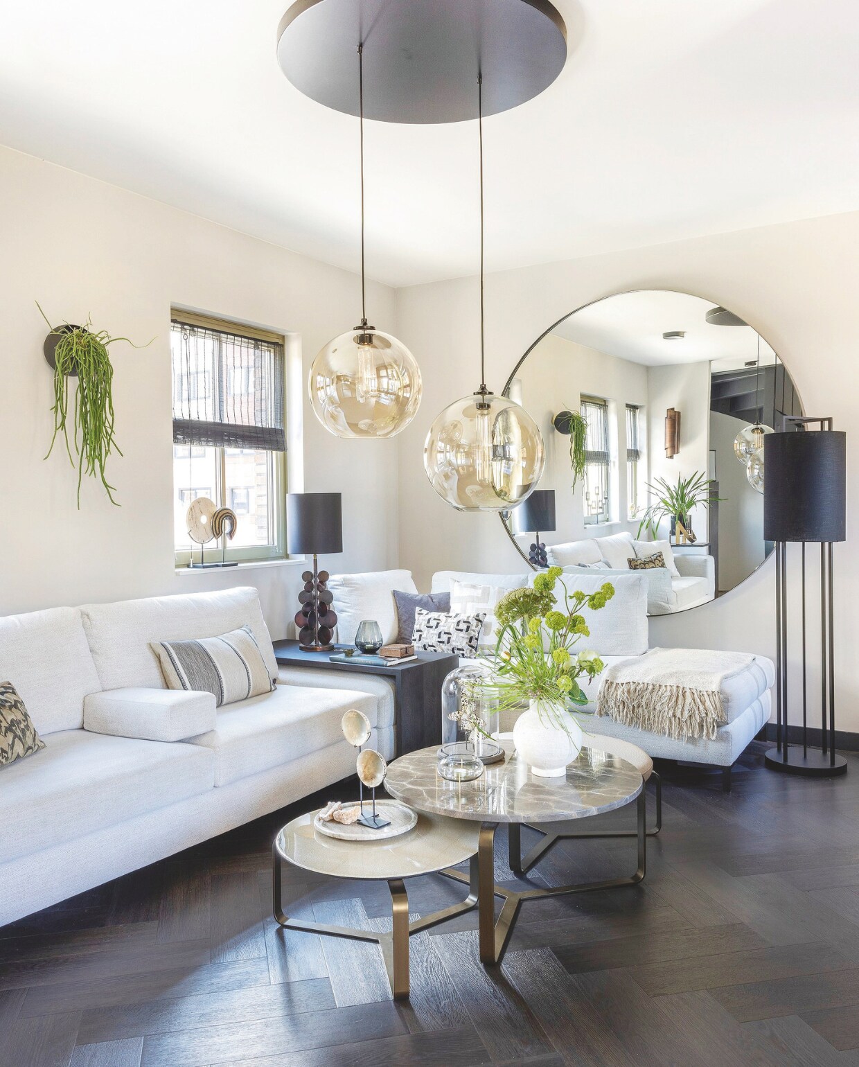 Elementenbank Lio komt van Keijser&amp;Co, de kussens erop zijn van Claudi. De salontafels zijn van Duran Interiors, de hanglamp erboven is van By Eve. Ronde spiegel Esquina komt van Duran Interiors. De kleur op de muur is Pelliccia van Carte Colori, op de vloer ligt pvc in visgraatmotief van Therdex. stijlvol wonen 09-2024 | fotografie Anneke Gambon