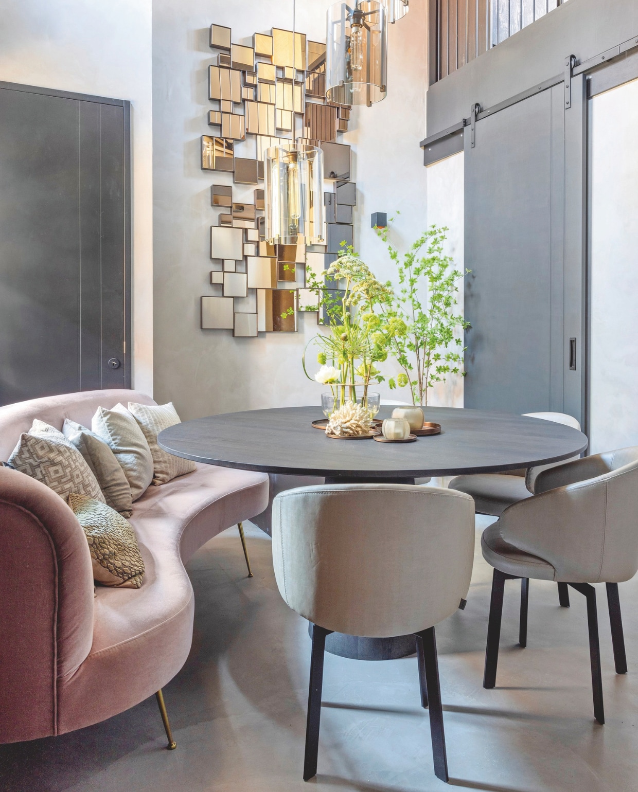 Eettafel Cone, bank Jackie en de stoelen komen uit de collectie van Keijser&amp;Co. De kussens zijn van Claudi en H&amp;M Home. Spiegels Hamilton op de muur komen van Rapture Interior Luxury, de lampen zijn van By Eve. Op de muur is gespaande kalkverf in de kleur Beton van Carte Colori aangebracht. Alle meubels zijn geleverd door Ann van den Berg van De Beukenhof Interieur &amp; Design. stijlvol wonen 09-2024 | fotografie Anneke Gambon