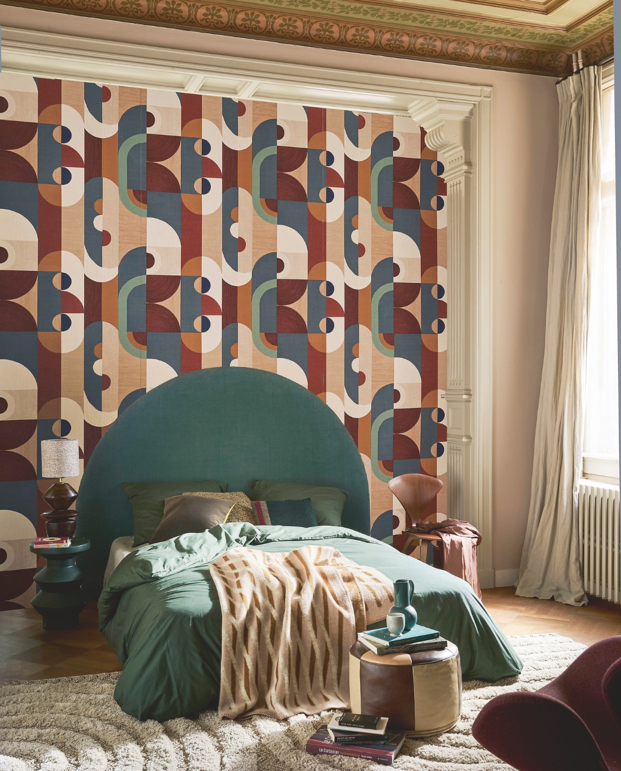 Muurverf Setting Plaster 231 van Farrow &amp; Ball (vestingh.nl). Behang Vassily uit de Mouvement-collectie nr. 75990610, 70 cm x 10 m (bxl), per rol € 148,50 (casamance.com). Hoofdeinde op maat (stoffeershop.nl), met stof Linara in kleur Bonsai van Romo Fabrics, 140 cm breed € 66,50 (romo.com). Katoenen dekbedovertrek, 220x240 cm € 34,99 (hm.com). Wollen deken van Roros Tweed, 135x200 cm € 229,- (debijenkorf.nl). Vintage Norman Cherner eetkamerstoel € 600,-, vintage fauteuil Swan van Arne Jacobsen in bordeauxrood € 1850,- (@iconic_objects). Vintage vloerkleed, 195x290 cm € 875,- (bestwelhip.nl), leren poef € 85,- (redesignvintage.nl). Groene bijzettafel Rook, 48 cm (h) € 254,- (versmissen.nl). Tafellamp Venue van Be Pure Home, 50 cm (h) € 139,-, zwart-groen sierkussen van HKLiving € 36,99, sierkussen Birgit van by Fonq  € 26,35 (vtwonen.nl). Petrolblauwe kan van Raawii € 75,- (groenenakker.nl).  Overig privébezit. vtwonen 11-2024 | styling Cleo Scheulderman | fotografie Jeroen van der Spek