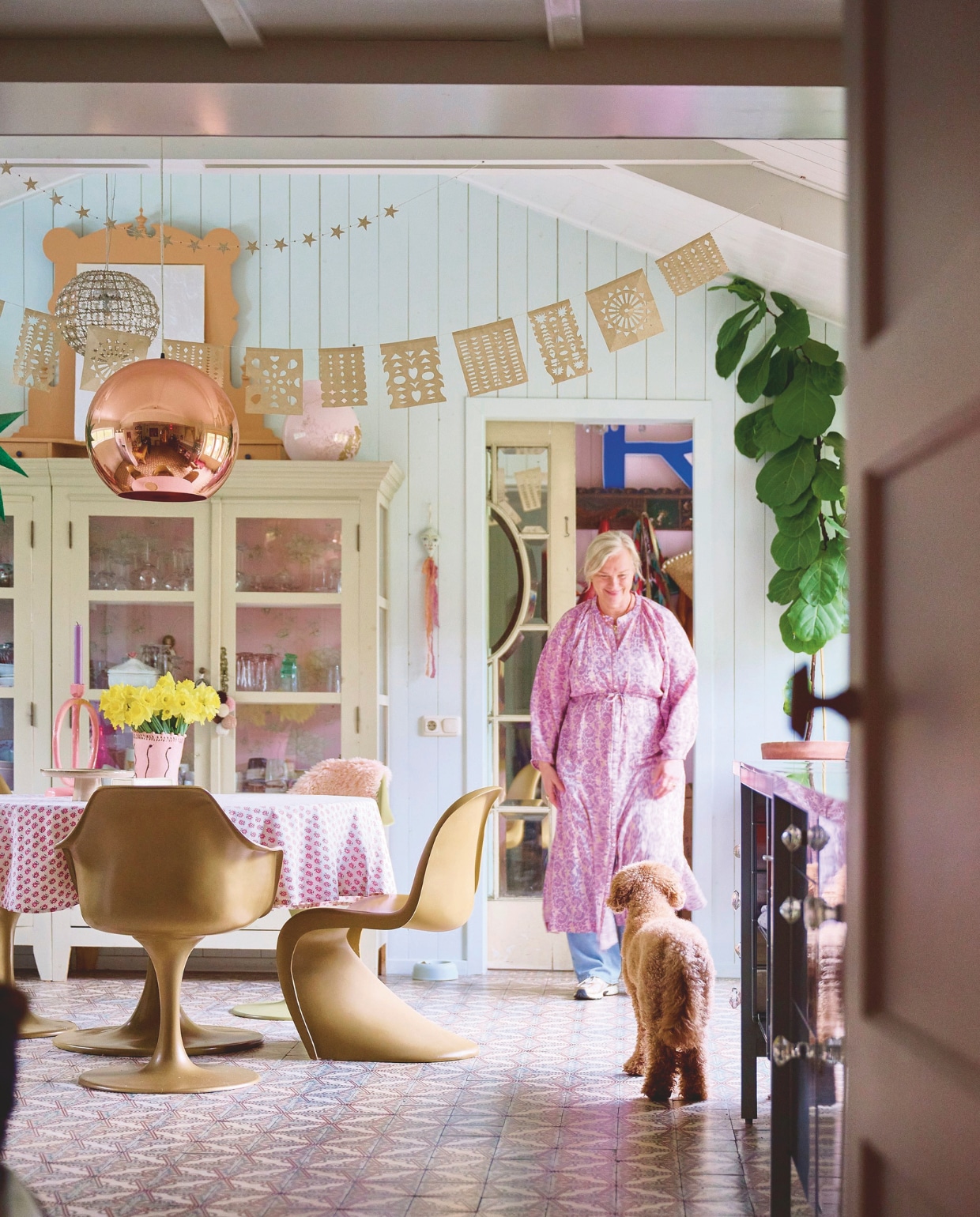Muurkleur Pavilion Blue van Farrow & Ball, tegelvloer Jan van IJken, keuken Ikea, aanrechtblad lokale keukenhandelaar, servieskast Opsetims, eettafel en stoelen Household Hardware. Tafelkleed, hanglamp achter de koperen lamp, kaars en glazen Sissy-Boy. Sterrenslinger White cube, Mexicaanse slinger Sukha, kandelaar Junoon by Janice, vaas The English Boys, taartschaal Kwantum, vaas op kast Ikea, hangpop Skippy Cotton, plant en pot tuincentrum.
