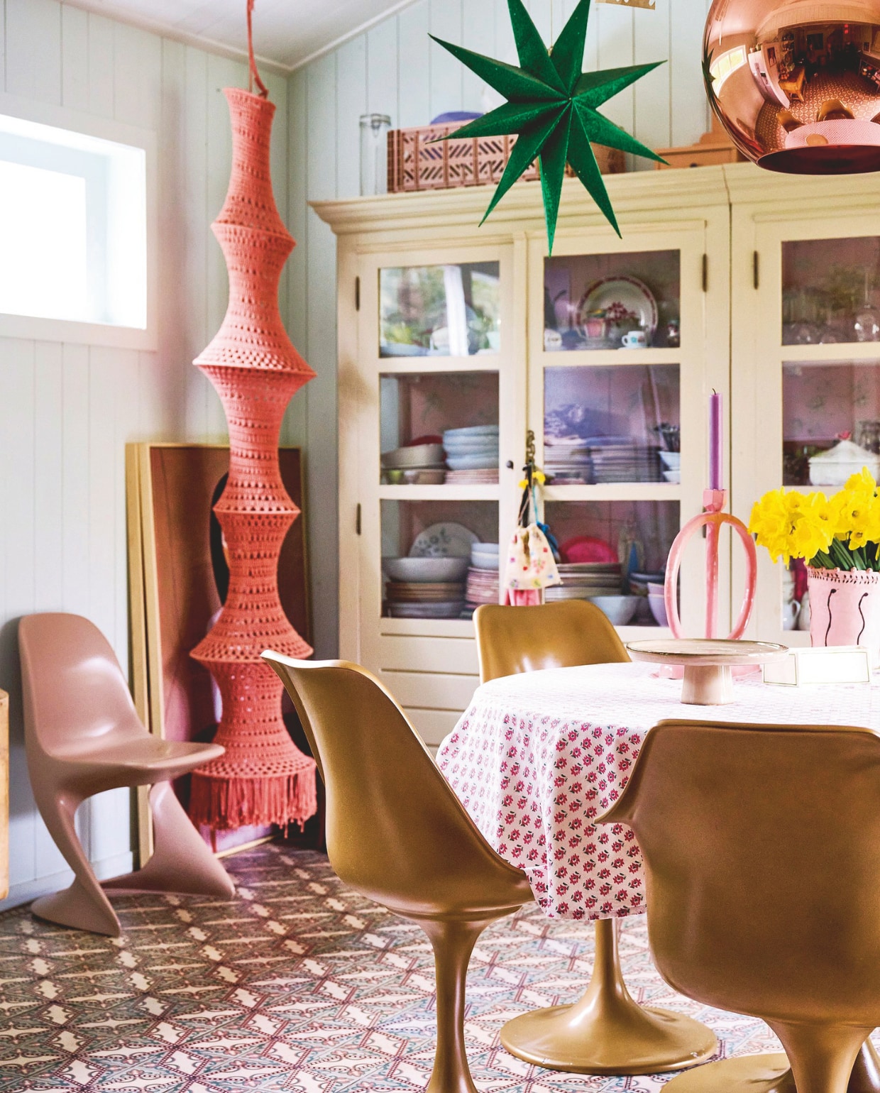 &lt; Muurkleur Pavilion Blue, servieskast Opsetims in Off White van Farrow &amp; Ball, tegelvloer Jan van IJken, eettafel en stoelen Household Hardware, tafelkleed Sissy-Boy, kandelaar Junoon by Janice, vaas The English Boys, taartschaal Kwantum, macramélamp Elpelut, groene ster Onstock, mand op kast Hay. vtwonen 10-2024 | styling Liza Wassenaar | fotografie Sjoerd Eickmans