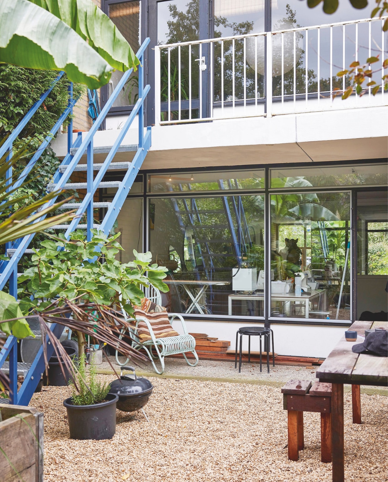 Blauwe trap en rotanstoel vintage. Kussens en zwarte krukken Ikea. Tuintafel en kruk eigen ontwerp. vtwonen 11-2024 | styling fietje bruijn | fotografie alexander van berge