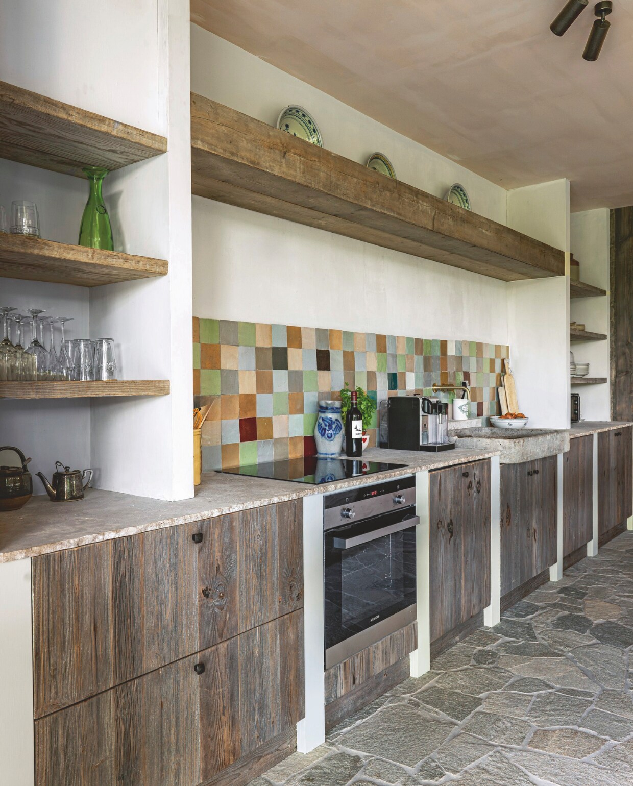 De keukenkasten zijngemaakt van oude grenen panelen. Het werkblad van natuursteen van Reumers Stone Creations kreeg een gehamerde rand waardoor het bruter oogt. Landelijk wonen 06-2024 | Fotografie Claude Smekens