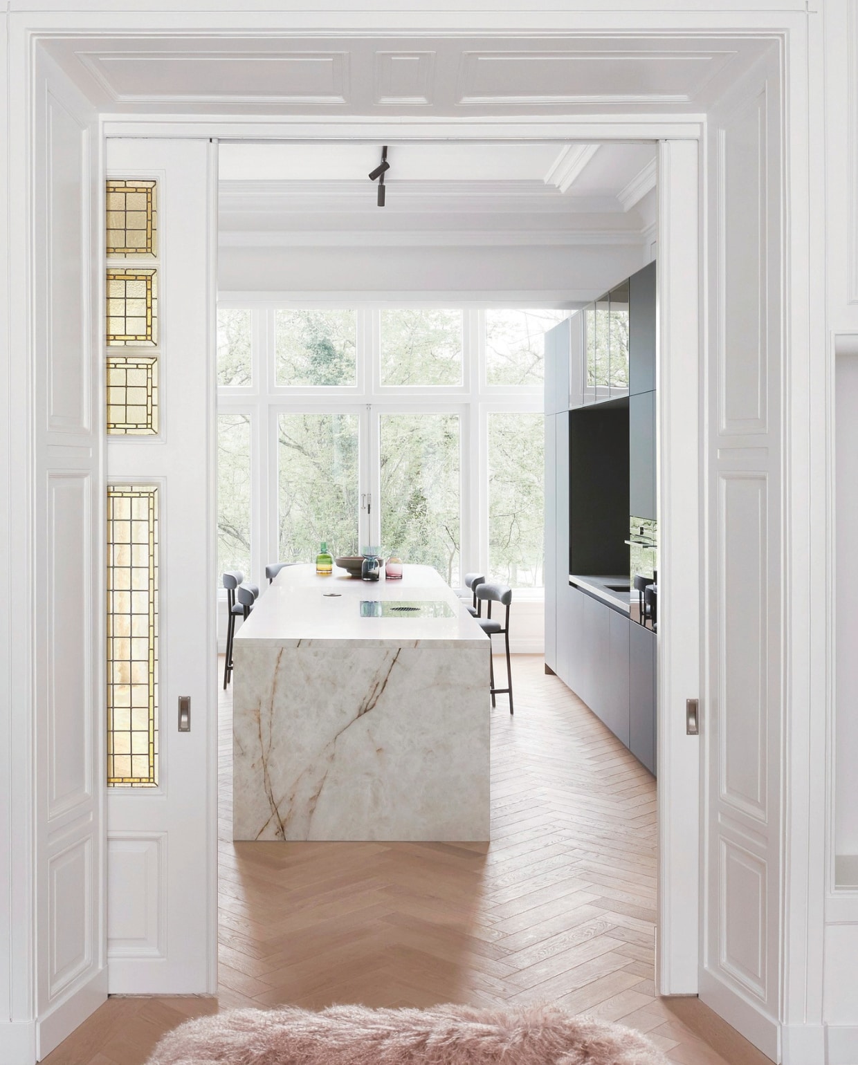 De op maat gemaakte marmeren keuken en zwart houten opbergruimte met apparatuur zijn maatwerk, krukken Font Light van Møbel Copenhagen. stijlvol wonen 07-2024 | Styling Barbara Berends | Fotografie Kasia Gatkowska