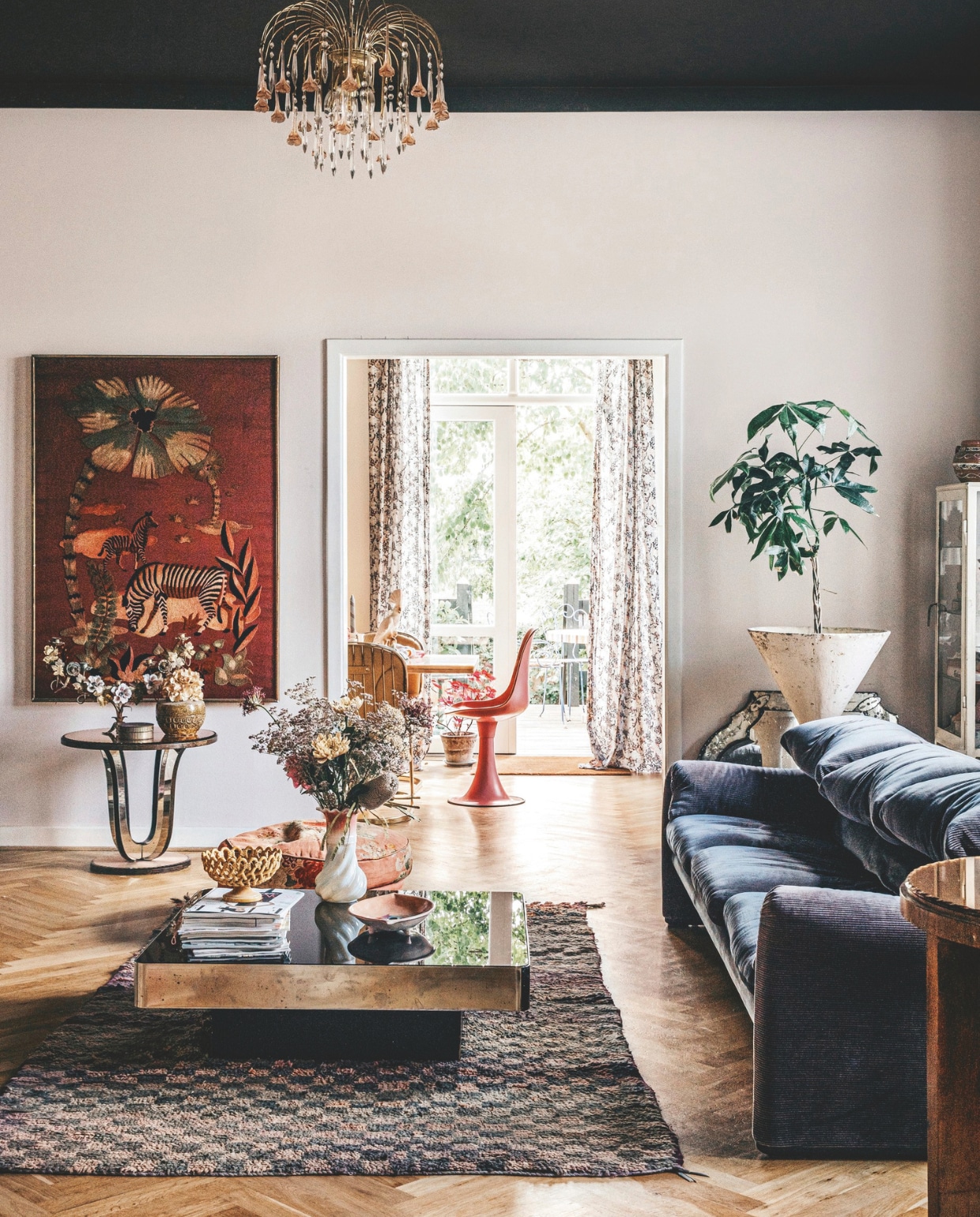 Oude Franse tissuedozen gevonden op een Franse vlooienmarkt, spiegel vintage Murano. Bank, salontafel, witte vaas, bijzettafel, vaas op bijzettafel, schaal en schilderij vintage. Vintage plantenbak ontworpen door Willy Guhl. Alle accessoires in huis zijn door Maria zelf via contactpersonen voor haar winkel of op vlooienmarkten in België, Frankrijk en Italië gevonden.
