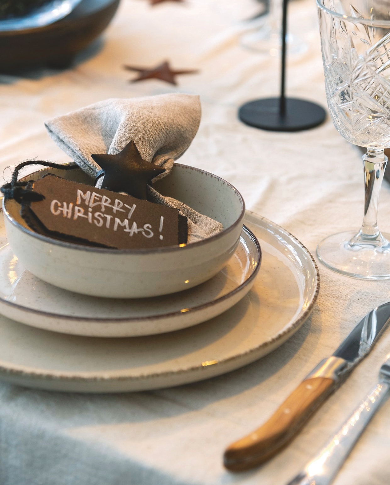 Feestservies van Palmer en een facet geslepen wijnglas van Blomus. Een mooi detail: de ster en het Merry Christmas-kaartje die het linnenservet sieren. vtwonen landelijk 07-2024 | fotografie Jonah Samyn