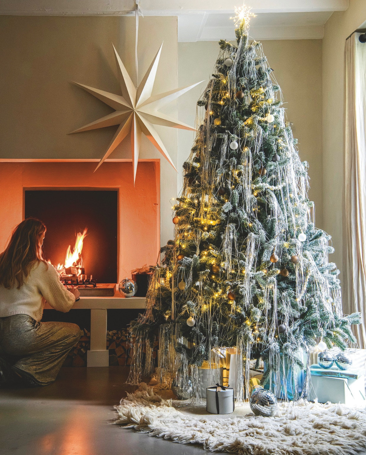 Design-kerstboom zilver | Kerstboom Nordmann € 55,- (buitengoeddeboomgaard.nl). Kartonnen ster XXL van vtwonen, 110x110 cm (bxh) € 29,92, zilveren en witte lametta, per pak € 4,49, parelslinger van vtwonen, 100 cm (l) € 49,95 (vtwonen.nl/shop). Vloerkleed Norte, wol en katoen, 150x200 cm € 585,- (fermliving.nl). Discoballen van House of Seasons, 10 cm (Ø), set van 2 € 5,50, en 25 cm (Ø) € 24,95 (vtwonen.nl/shop). Piek met ledlicht Glow van House Doctor € 44,95 (strong-desire.nl). Matte glazen kerstballen Juhla in antraciet, bruin en helder, set van 6 € 24,95 (blomus.com). Overig privébezit. vtwonen 12-2024 | styling Marit Saladini | fotografie Louis Lemaire