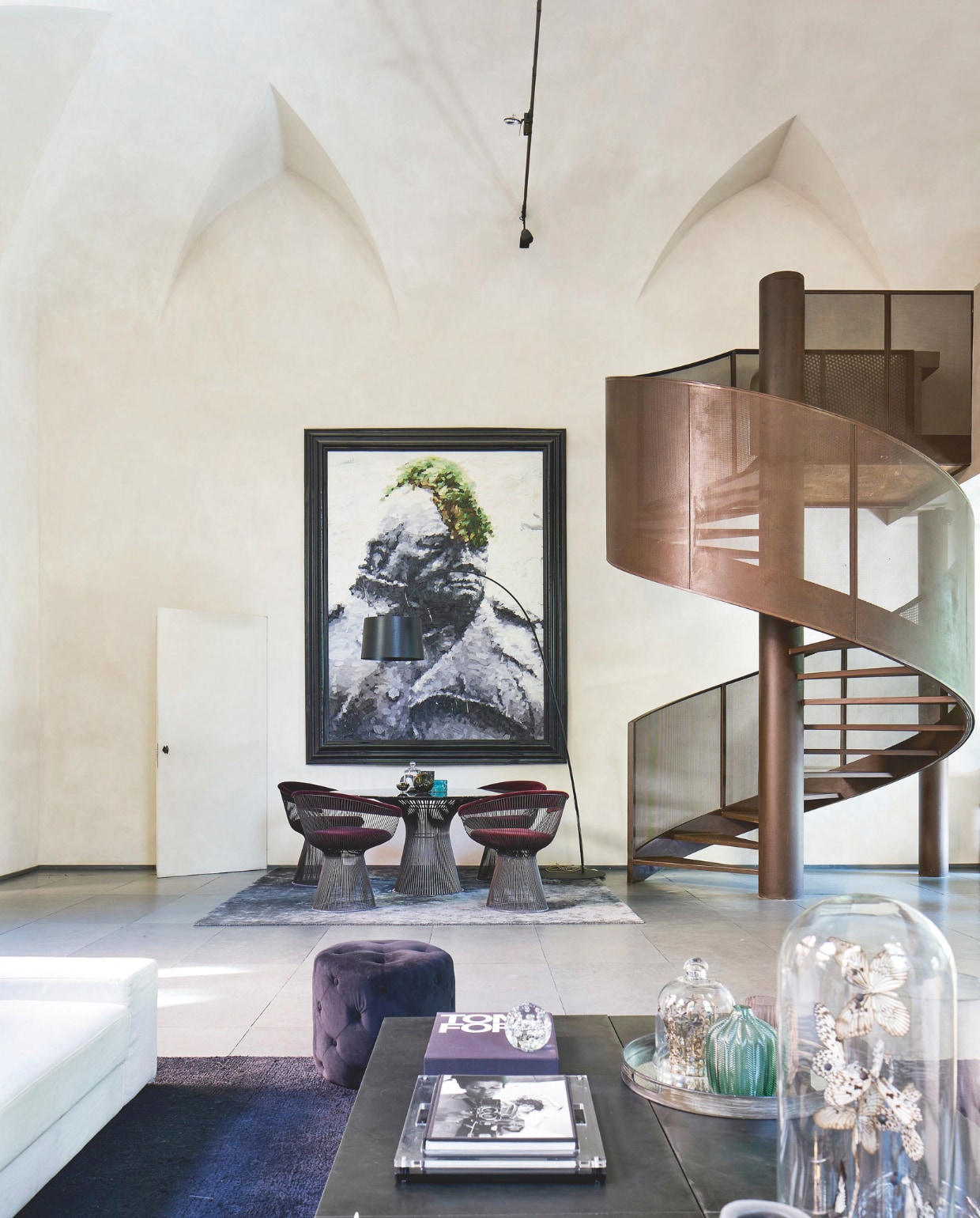 Spiraalvormige trap van microgeperforeerd cortenstaal. Ronde tafel en stoelen van Warren Platner voor Knoll, afgewerkt in auberginekleurig fluweel. stijlvol wonen 07-2024 | Productie Living Inside | styling en tekst Francesca Davoli | Fotografie Fabrizio Cicconi