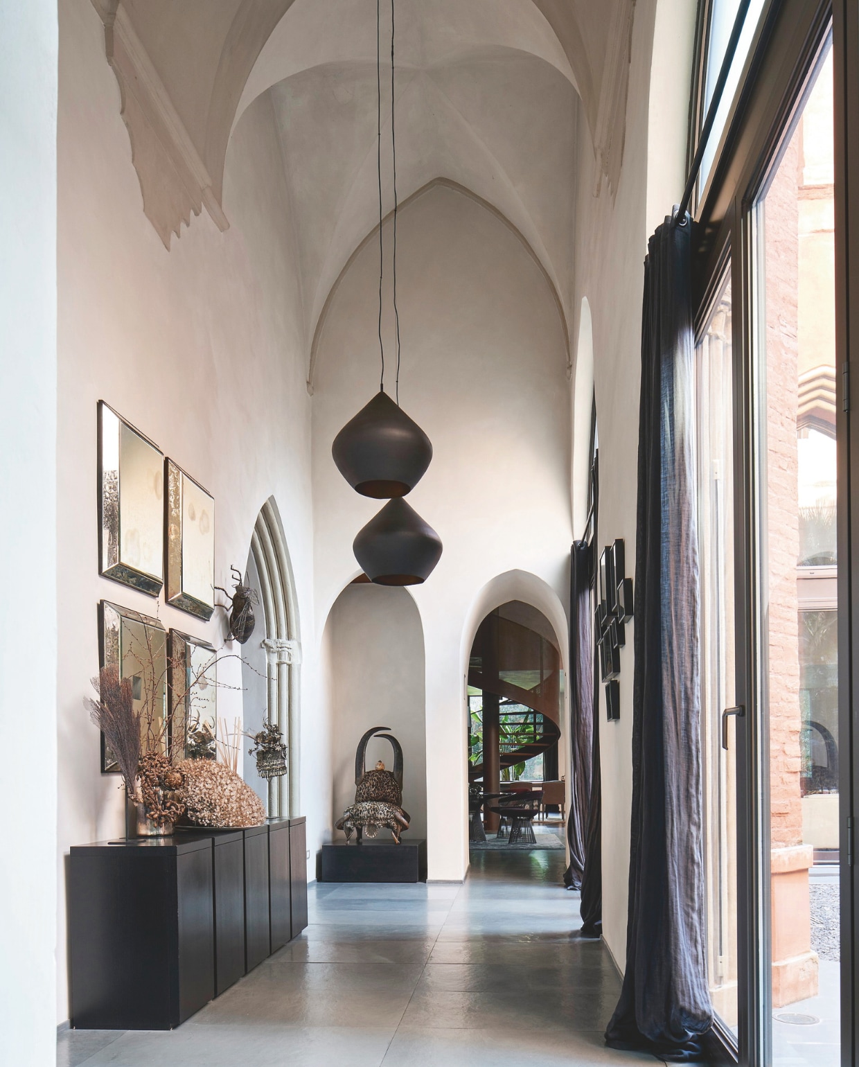 Hoge gang die naar de woonkamer leidt. De kast is op maat gemaakt. Aan de wand Indische diamantspiegels, de hanglampen zijn van Tom Dixon. De stoelsculptuur is van Michel Haillard. stijlvol wonen 07-2024 | Productie Living Inside | styling en tekst Francesca Davoli | Fotografie Fabrizio Cicconi