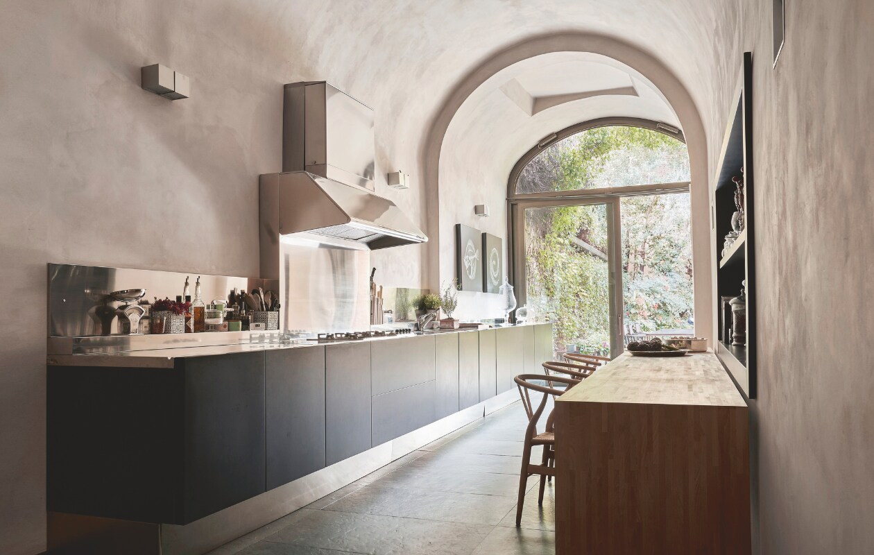 De matzwart gelakte keuken is maatwerk. Aan de beukenhouten tafelstaan stoelen CH4 van Carl Hansen &amp; Søn. stijlvol wonen 07-2024 | Productie Living Inside | styling en tekst Francesca Davoli | Fotografie Fabrizio Cicconi