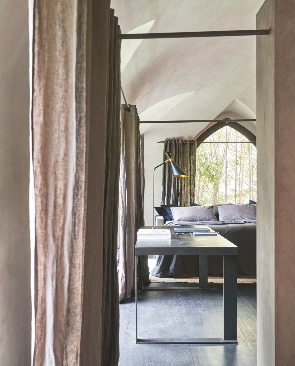 Slaapkamer met uitzicht op de tuin. De tafel is gemaakt van gepolijst messing en leer. De lamp is vintage uit de jaren 50. stijlvol wonen 07-2024 | Productie Living Inside | styling en tekst Francesca Davoli | Fotografie Fabrizio Cicconi