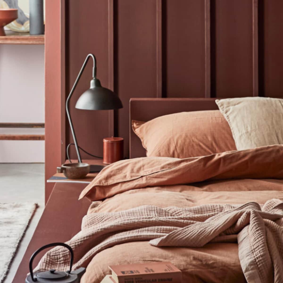 vtwonen collectie (Muurverf Red Earth (voorste wanden en kolom), Washed Lilac (achterwand), lakverf Terra (bed en headboard)) M.m.v com-anders.nl (op maat gemaakt headboard en bed), vtwonen.nl (tafellamp Orion, beddengoed Natural Stone in kleur Terra, roze sprei en stoel van hout en leer uit de vtwonen collectie, groot bord met gezicht van Ferm Living), nordal.eu (terracotta vaas met oor, vloerkleed, grote terracotta schaal, theepot, karpet), iblaursen.com (quilt op stoel, roze linnen kussen), maisonnl.com (bruin rond leren potje, bruin boek). Overig privébezit. vtwonen 09-2020