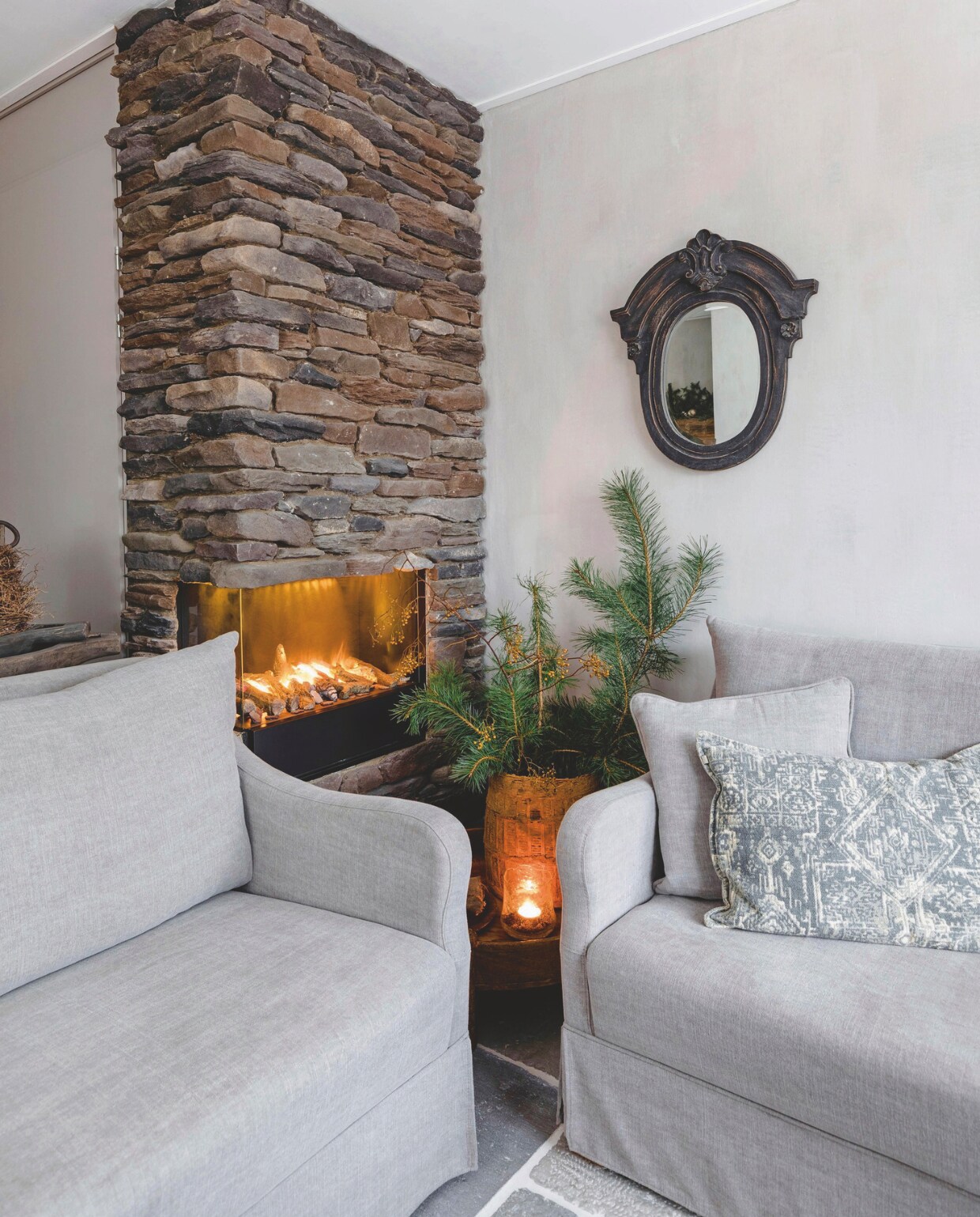 De schouw is door Richard en Hilda zelf bekleed met stenen uit Italië. De bank, fauteuil en spiegel zijn gekocht bij Rust &amp; tiek. vtwonen landelijk 07-2024 | Styling Rust &amp; tiek | Fotografie Corine Hoge Bavel-Jansen
