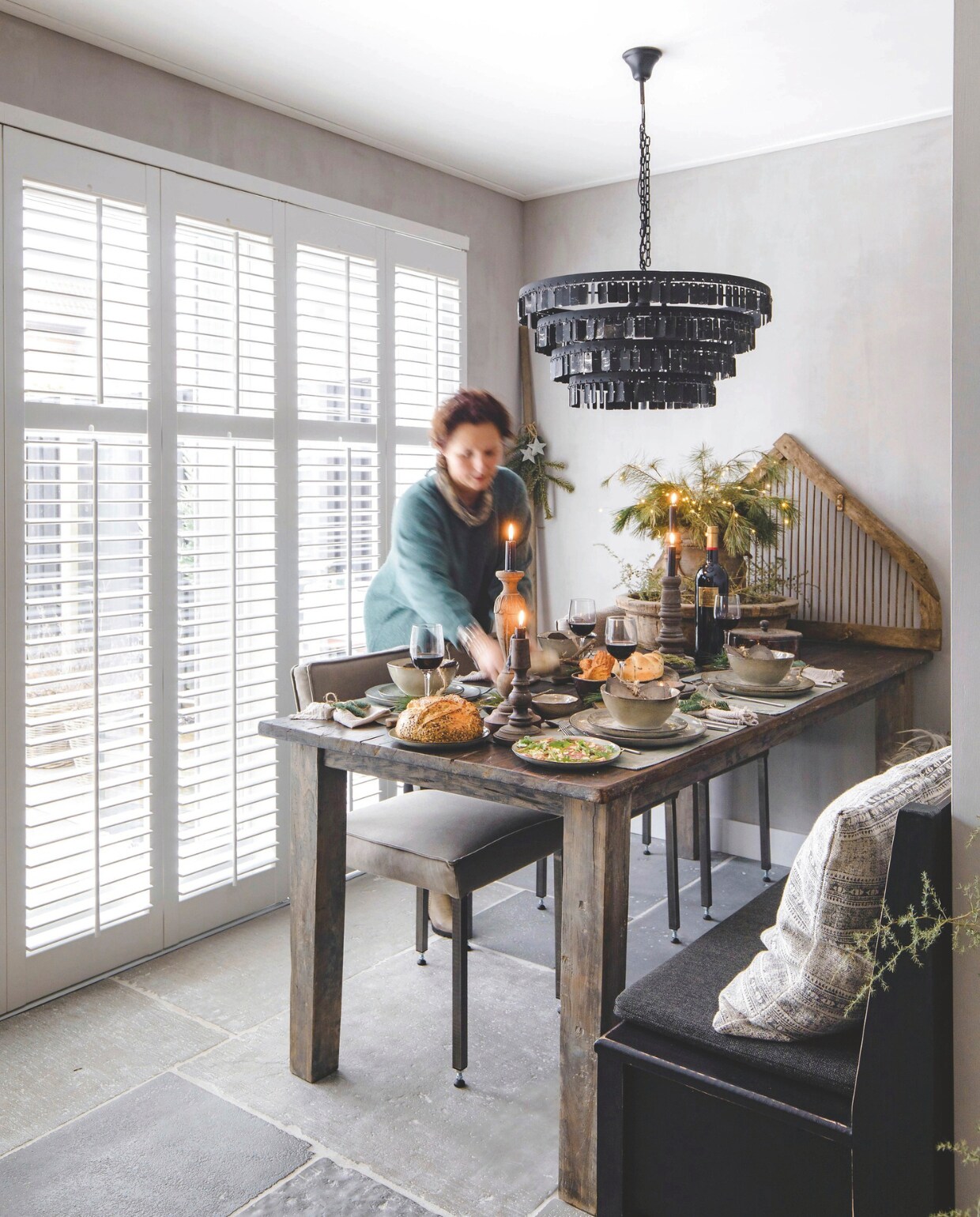 De eettafel komt van Met Landelijk Label, de bank van Les Brocanteurs. De hanglamp is van Rust &amp; tiek, net als de kandelaren, de houten onderborden en de amuseplankjes. Aan het eind van de tafel staat een hooiruif van Het Olde Jagthuys. De shutters  zijn van Veneta. vtwonen landelijk 07-2024 | Styling Rust &amp; tiek | Fotografie Corine Hoge Bavel-Jansen