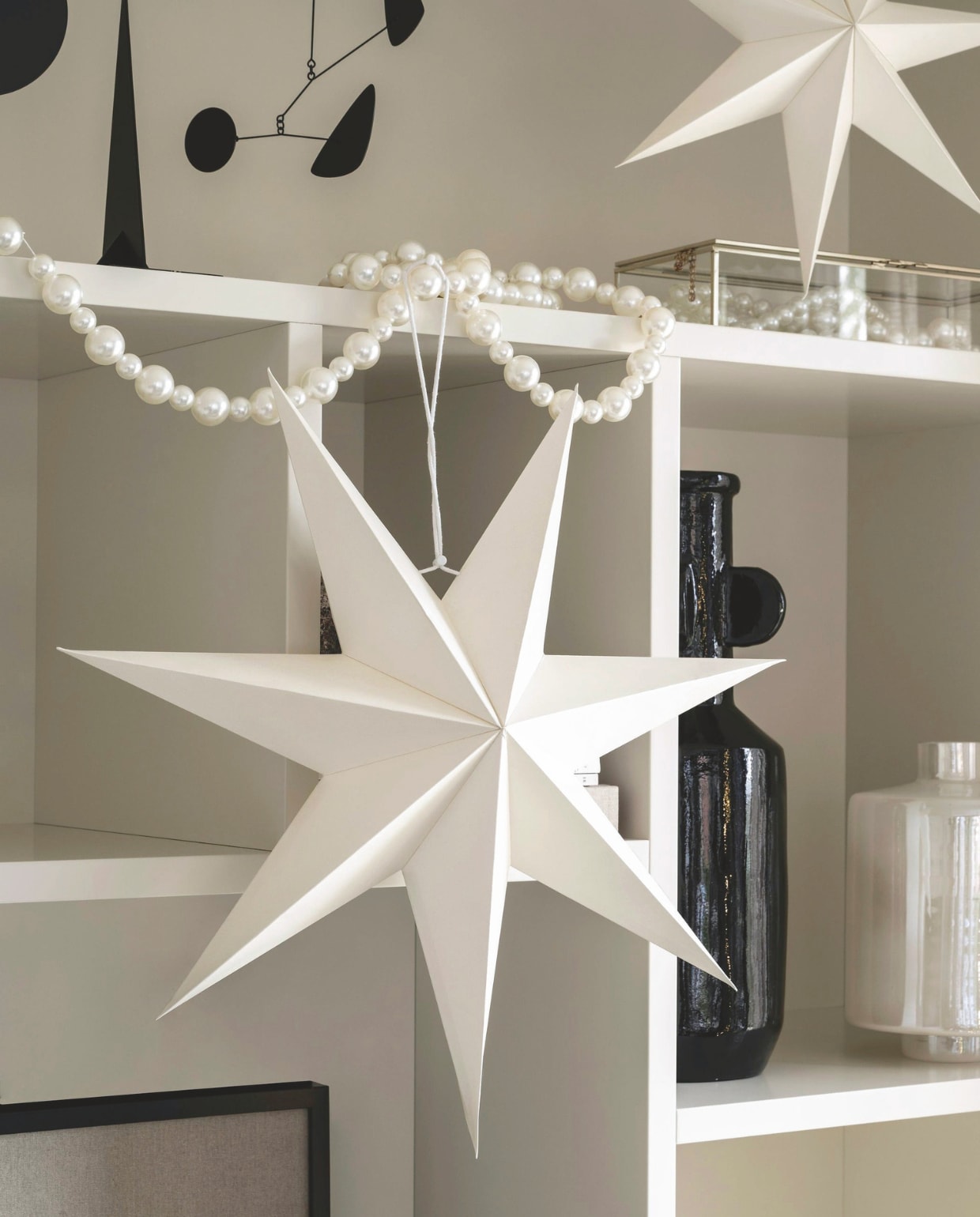 Guirlande Pearl, 200 cm (l) € 64,95. Papieren kerstster Pearl met parelmoer, 48 cm (Ø) € 14,95, 60 cm (Ø) € 19,95. Glazen vaas met parelglans, 20x30 cm (Øxh) € 49,95. vtwonen 12-2024 | styling Kim van Rossenberg | fotografie Stan Koolen