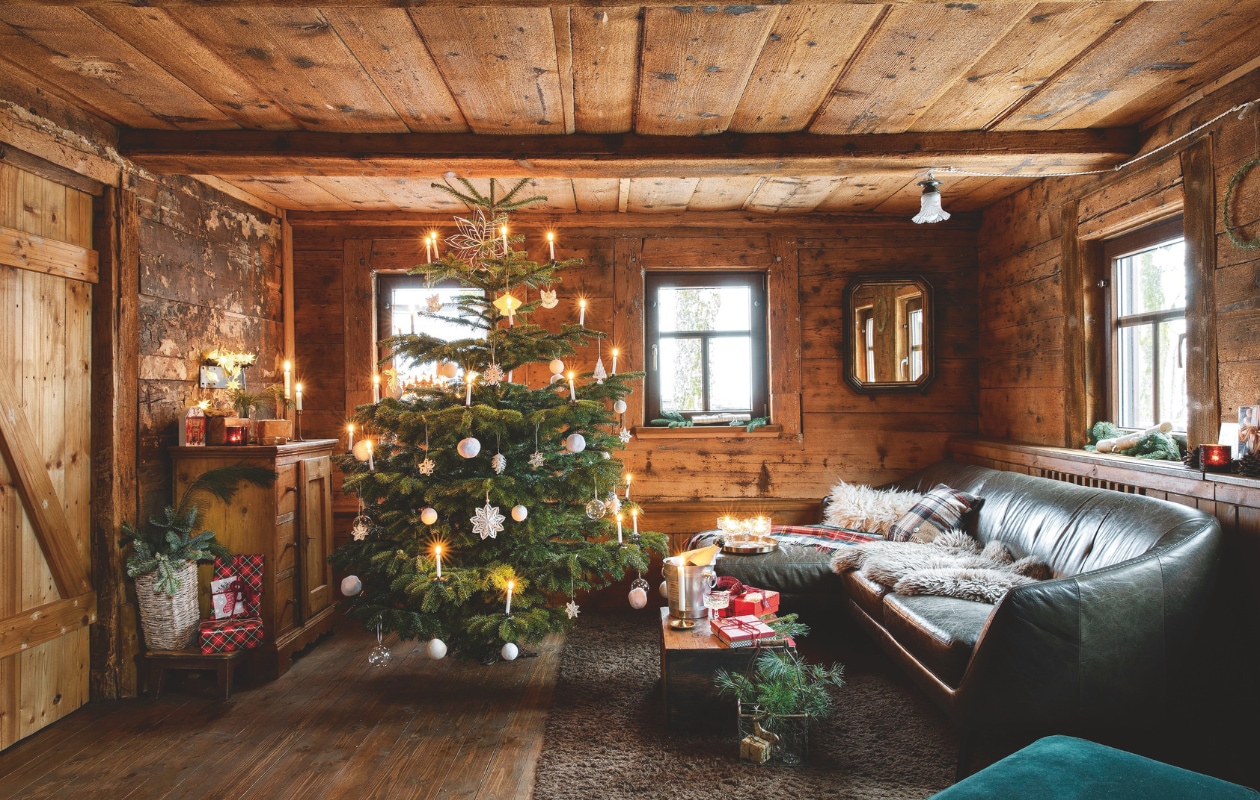 Het plafond ende muren van de zitkamer werden gerestaureerd. De houten vloer is gereconstrueerd. In de kerstboom hangen ornamenten van papier, vilt, glas en stro. vtwonen landelijk 07-2024 | styling Miriam Hannemann | fotografie André Reuter