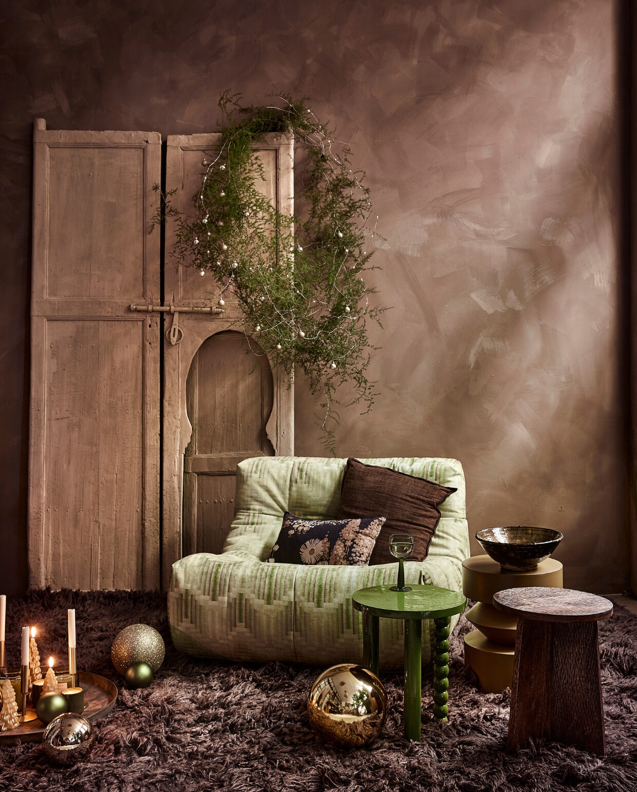 Fauteuil Lazy Lounge Chair, 105x105x75 cm (bxdxh) € 1795,-, bruin hoogpolig vloerkleed Fluffy in Espresso, wol en katoen, 200x300 cm € 1695,-(hkliving.nl). Groene acaciahouten bijzettafel Hava € 71,96, okergele metalen bijzettafel Bora € 125,-, mangohouten bijzettafel Lux € 99,95, keramieken theelicht € 5,95, kerstboomkaarsjes laag € 6,95, hoog € 9,95 (loods5.nl). Gouden kunststof kerstballen vanaf € 13,95 (kerstversiering.nl). Keramieken schaal op tafel € 49,95 (householdhardware.nl). Goudkleurige kandelaars laag € 7,50, hoog € 9,- (hema.nl). Groene glazen kerstbal, per 6 € 16,16 (bol.com). Gouden glazen kerstballen € 4,95 (xenos.nl). Krans zelfgemaakt. Overig privébezit. vtwonen 13-2023 | styling Moniek Visser | fotografie Peggy Janssen | assistentie Fenneke Deinema