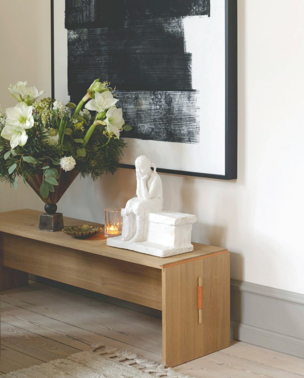 Bank Takt, sculptuur Hanne Warming, kunstwerk Akuart Home, kaarsen van Tine K Home, messing schaal van rommelmarkt, vaas Tage Andersen met erin amaryllis. vtwonen 12-2024 | styling rikke graff juel | fotografie christina kayser onsgaard