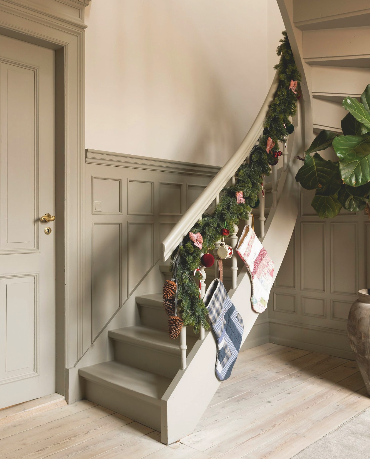 Lambrisering zelf ontworpen en gemaakt, kleur houtwerk Warm Grey van Jotun, kunstsparrengroen van het tuincentrum, kerstsokken@lillekirstejn waar Vivi de namen van de kinderen op borduurde, velours ballen Ikea, vintage trommels. vtwonen 12-2024 | styling rikke graff juel | fotografie christina kayser onsgaard