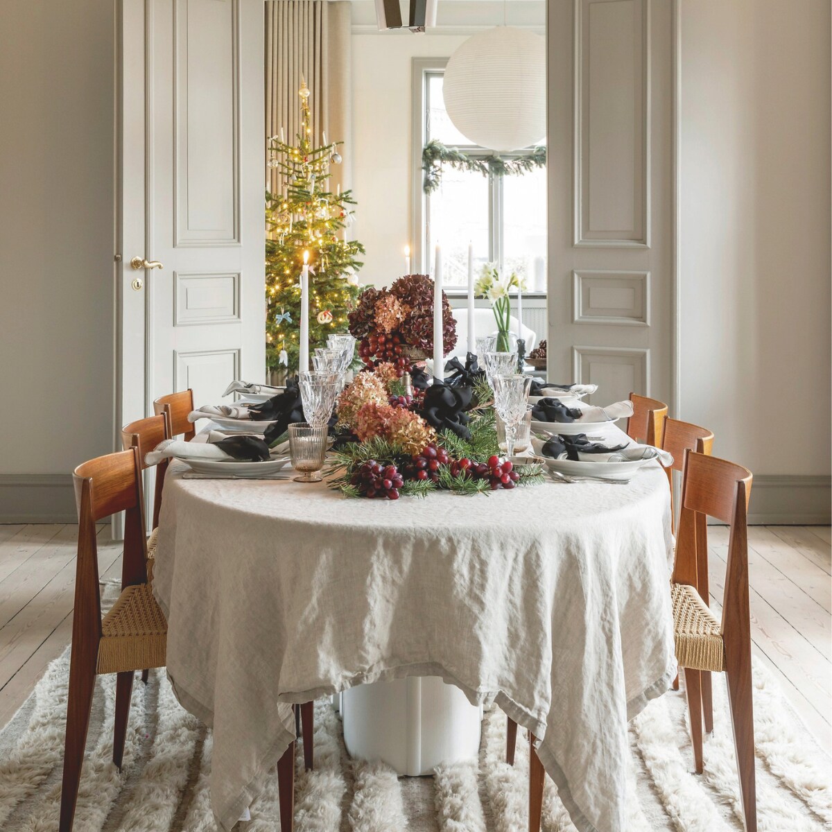 Linnen tafelkleed Nordal, zilveren borden Boho Habits, aardewerk Royal Copenhagen en rommelmarktvondsten, glaswerk vintage, servetten Broste Copenhagen, lamp Rubn, stoelen Pia van Poul Cadovius door DK3 Furniture, tapijt Jotex, stalen kunstwerk Kristian Jon Larsen. vtwonen 12-2024 | styling Rikke Graff Juel | fotografie Christina Kayser Onsgaard