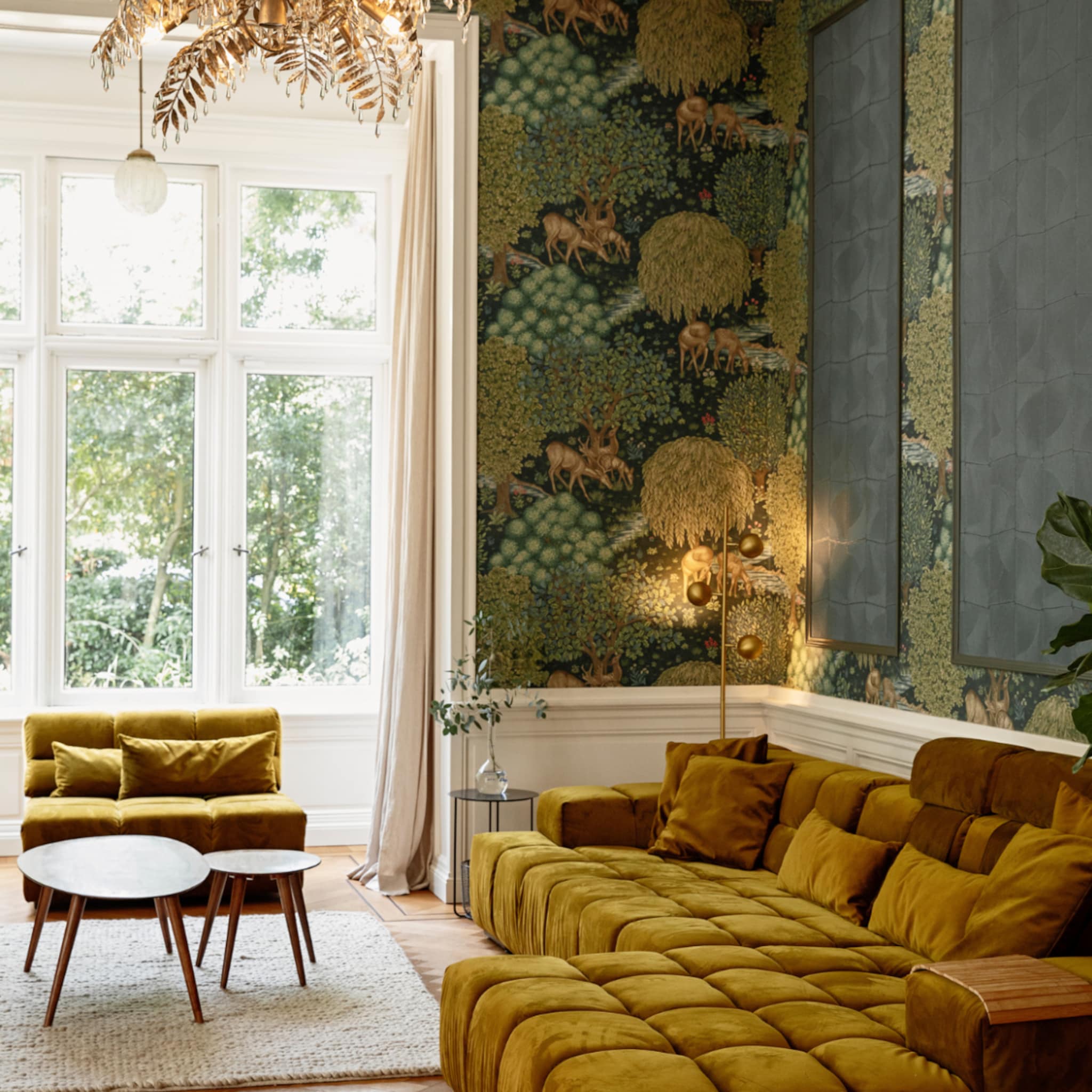 Okergele bank in een woonkamer met botanisch behang en een gouden hanglamp