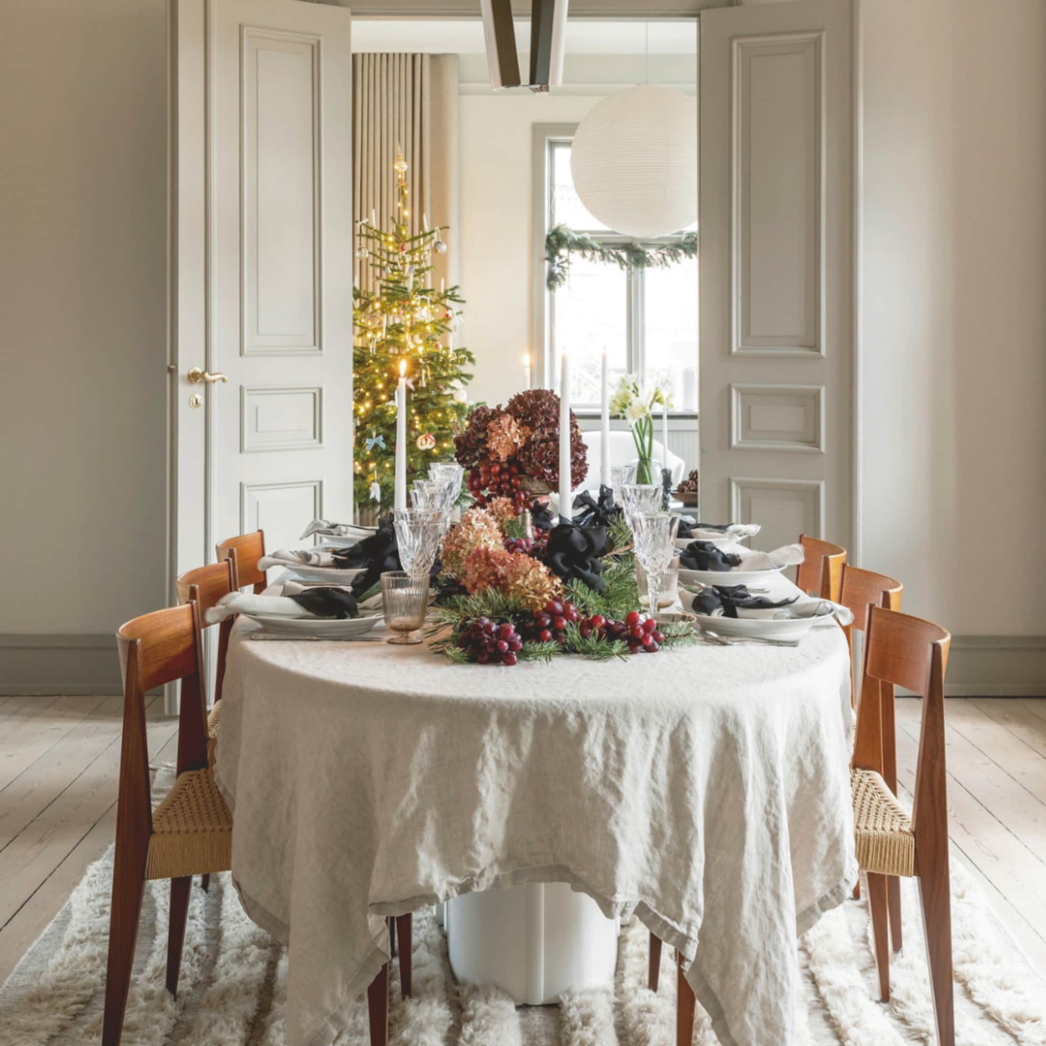 Klassieke woning met een kerstboom en gedekte eettafel vol kerstdecoraties