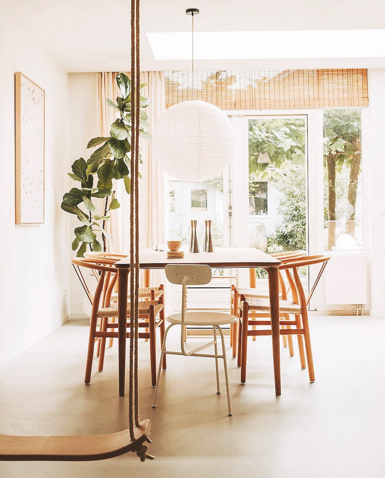 Gordijnen Zara Home, rolgordijn Kwantum, kunstwerk Maartje van den Noort, lamp Hay, eettafel Fawn van Gazzda, stoelen Loods 5, witte stoel Audo Copenhagen, schommel via ilovespeelgoed.nl.
