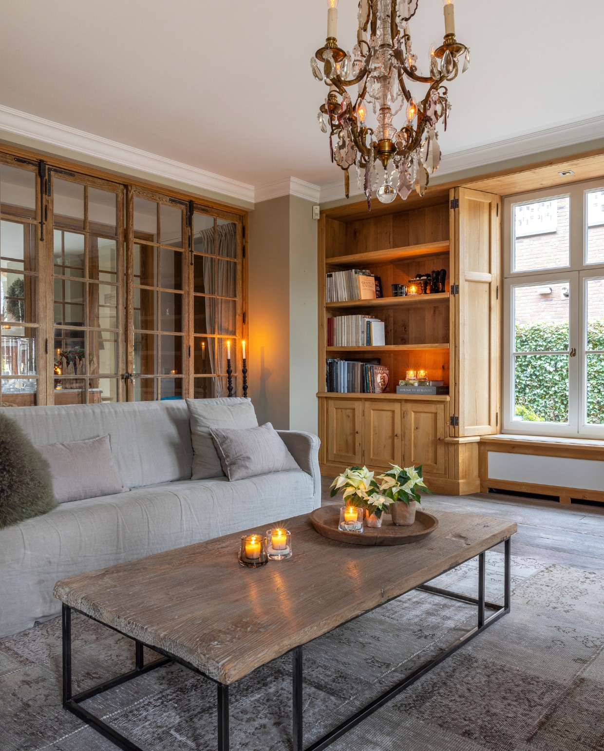 Antieke kristallen kroonluchter, oude eikenhouten deuren met ruitjes, tafel van een oude deur met een ijzerenonderstel, en houten vloer van’t Achterhuis. Het Vintage patchwork tapijt is van Perez Vloerkleden. De bank van Hoffz heeft een losselinnen bekleding. vtwonen landelijk 7-2024 | Fotografie Anneke Gambon
