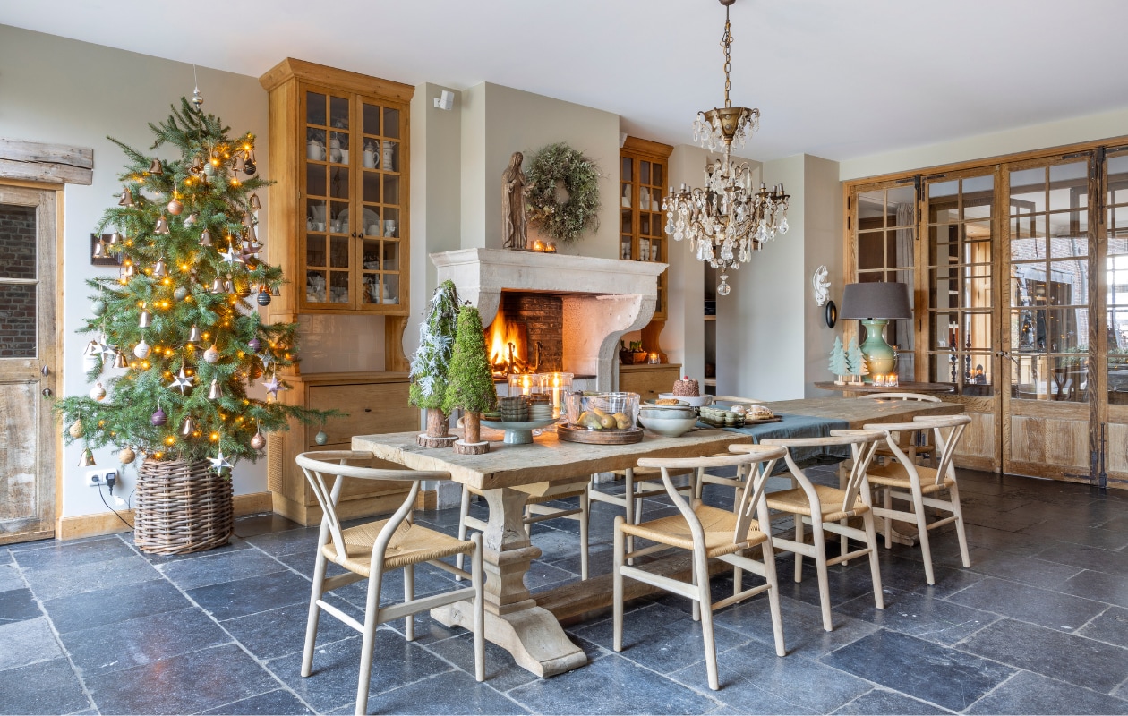 De oude eiken tafel is bijna vier meter lang en werd vervaardigd in het eigen atelier van ’t Achterhuis. Ook de eiken stoelen komen ervandaan. Boompjes van Style Rustique. In de kast een deel van Sarahs verzameling aardewerk en witjes van ’t Achterhuis. De kerstboom staat in een mand van Gommaire, alle decoratie is van’t Achterhuis. vtwonen landelijk 7-2024 | Fotografie Anneke Gambon