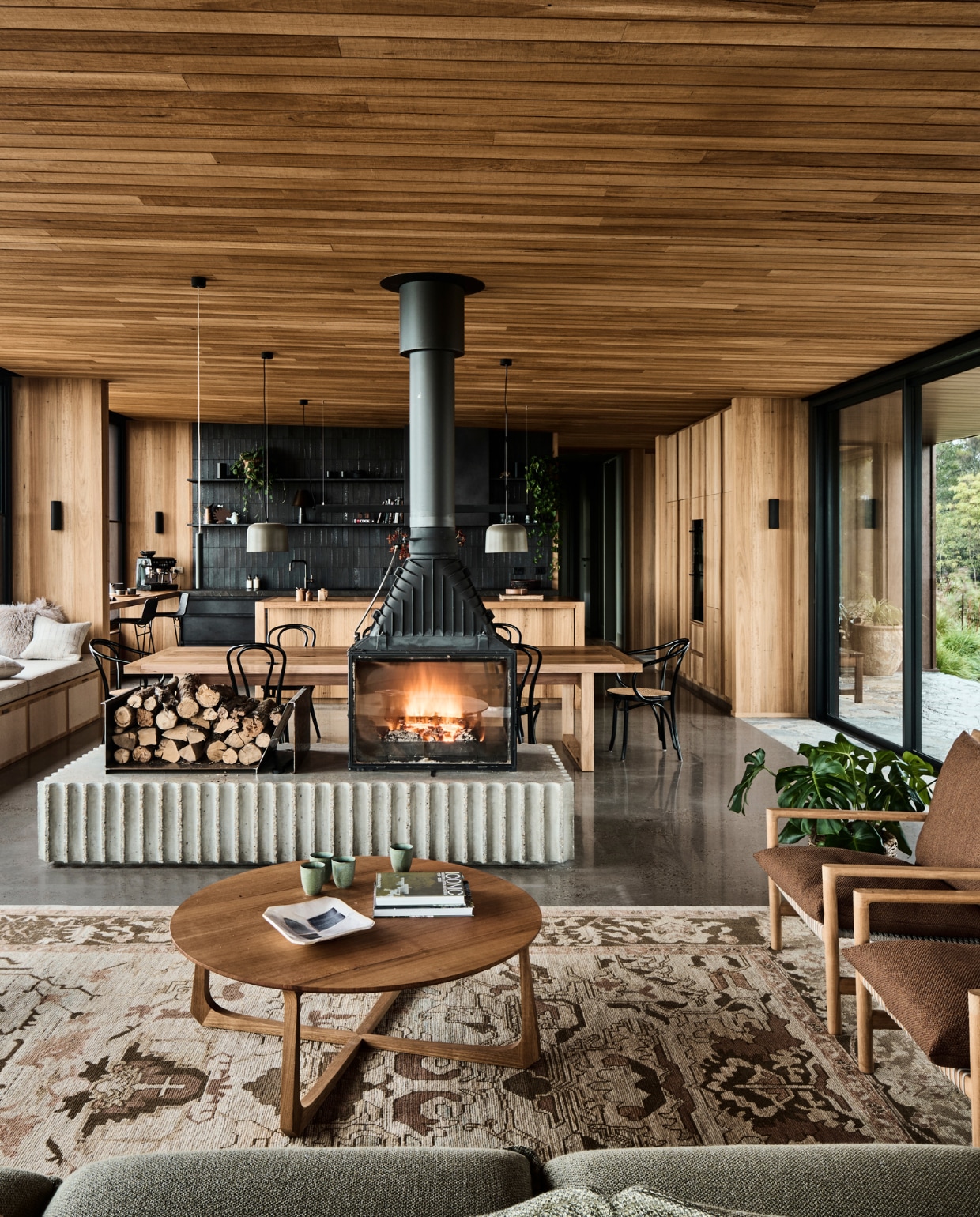 Tweezijdige hanghaard van Cheminées Philippe. Stoelen 18 en B9 van Thonet. De tafel is op maat gemaakt van gerecycled hout. Vloer van polybeton. stijlvol wonen 08-2024 | productie Living agency | fotografie Tom Blachford
