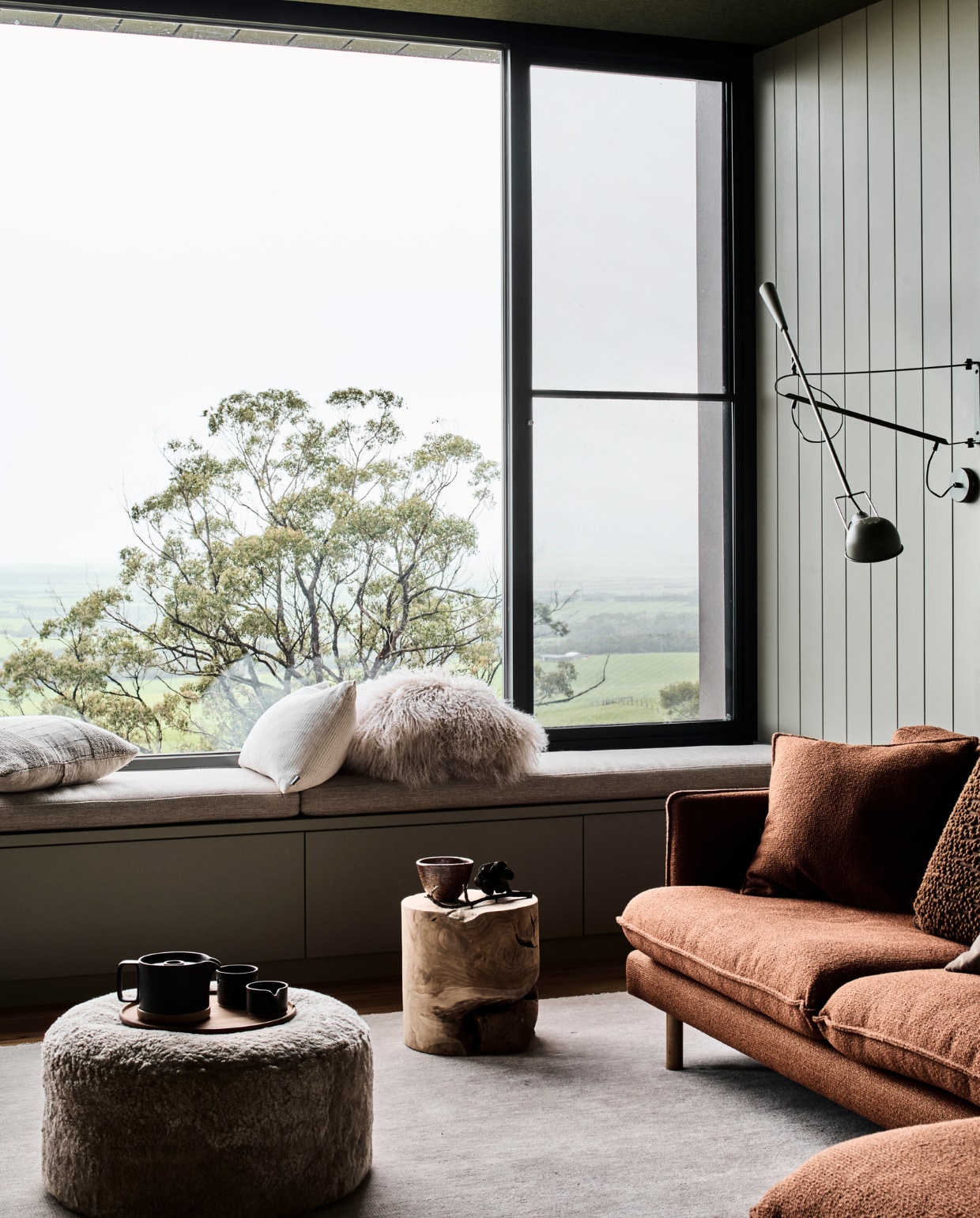 Wand bekleed met groefpanelen, gelakt in Forest Canopy van Dulux. Wandlamp Flos, bank Archie van Arthur G, poef Curly van Domo, harig kussen Nordic Adobe. stijlvol wonen 08-2024 | productie Living agency | fotografie Tom Blachford