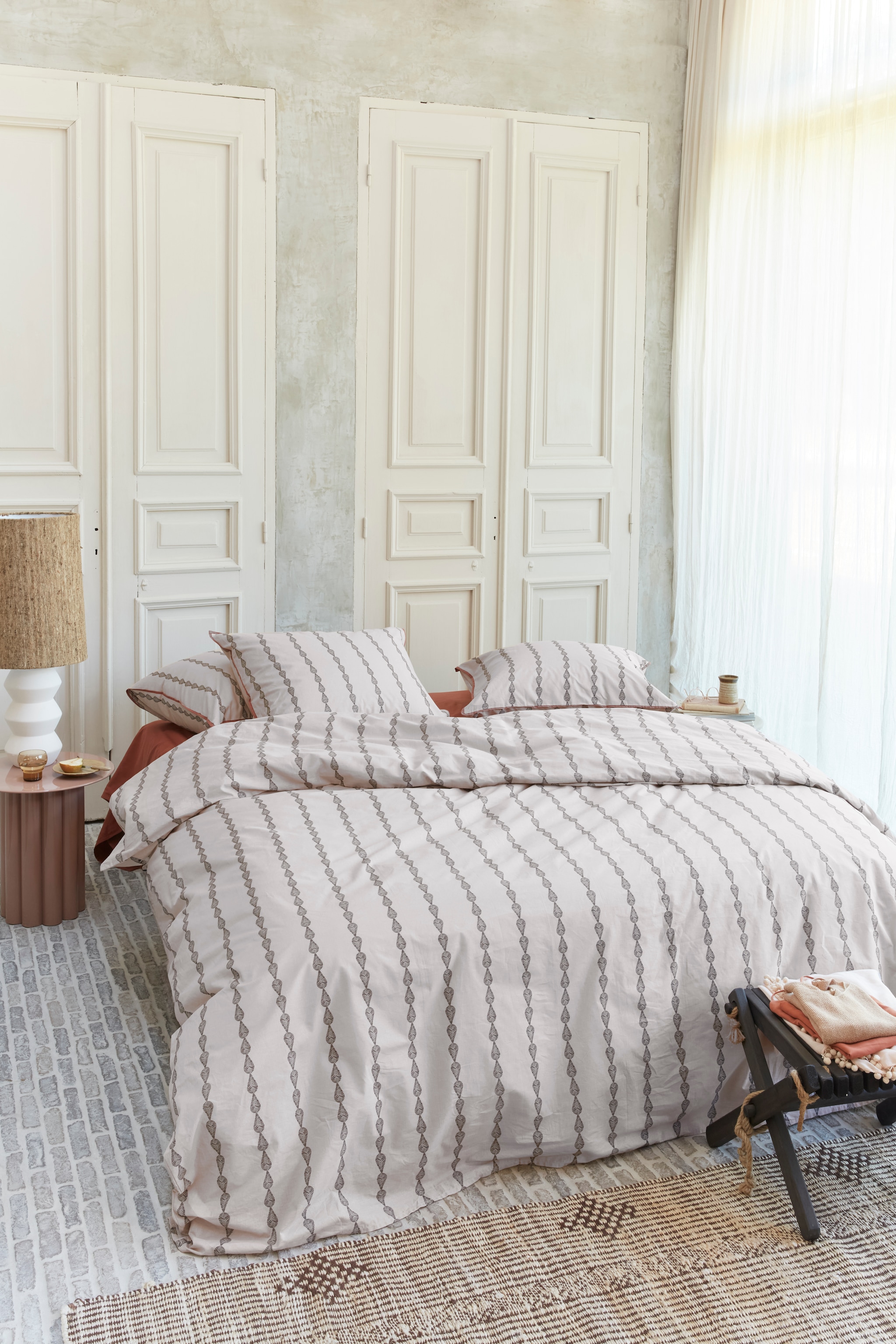 Katoenen dekbedovertrek Up Side Down in Zand vanaf € 49,95. M.m.v. by-boo.com (nachtkastje), kwantum.nl (lamp), hkliving.com (waterglas en vloerkleed). Overig privébezit. vtwonen 04-2025 | styling Kim Timmerman, Danielle Verheul | fotografie Richard Smit