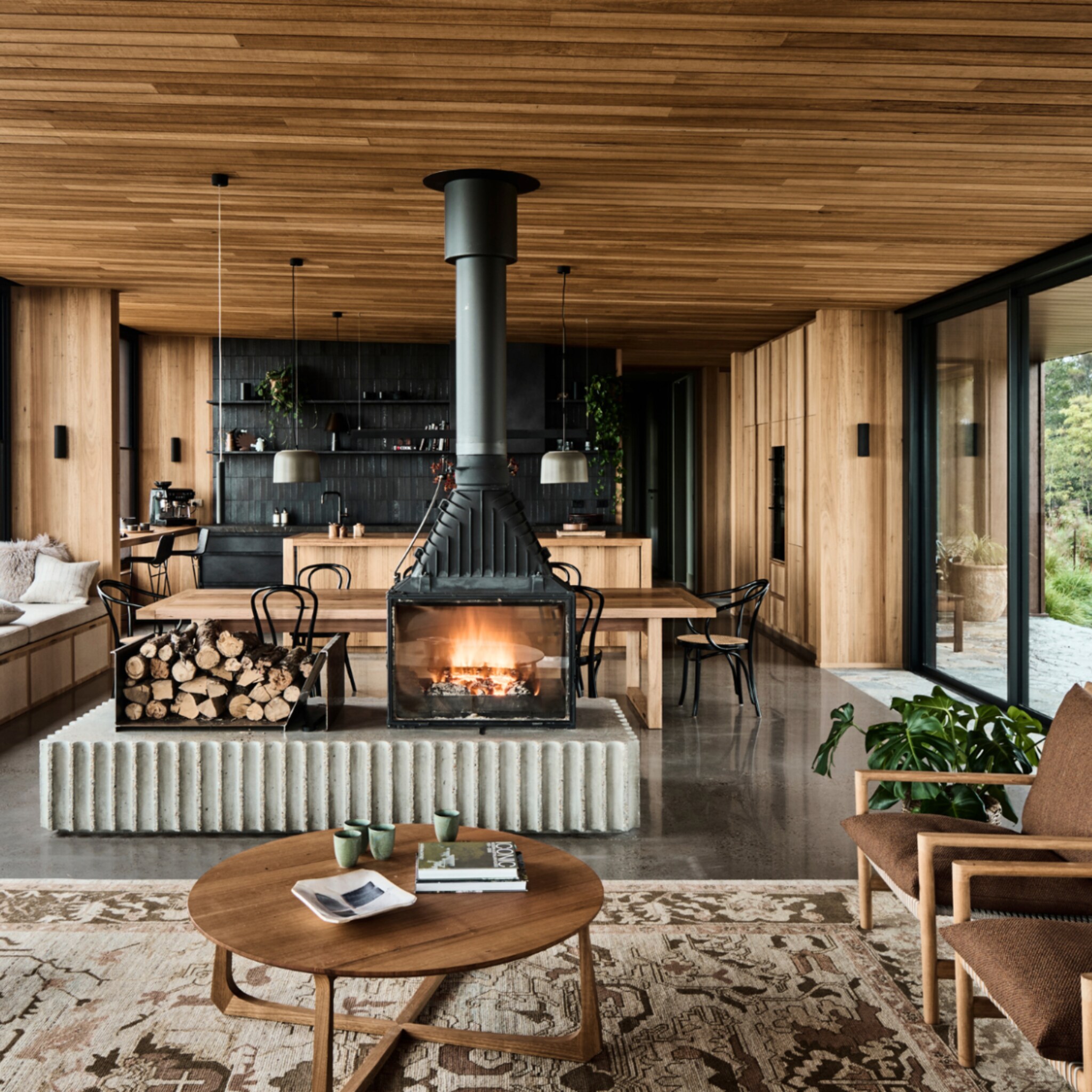 Woonkamer en keuken vol natuurlijke materialen met een plafond van hout