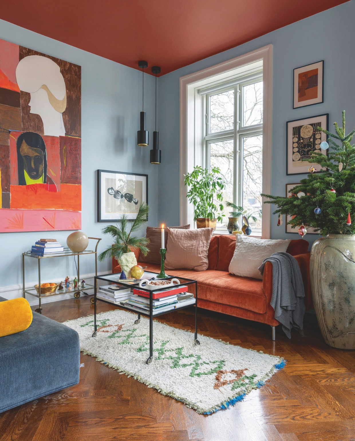 Jette schilderde de wanden in de woonkamer lichtblauw-groen en het plafond sienna terracotta. Banken Eilersen, kussens Merci en Stilleben, Marokkaans vloerkleed By Fribert, salontafel Please Wait To Be Seated, lamp op vintage trolley Helle Mardahl, grote pot Christian Bruun gekocht op Arts and Crafts Market Kopenhagen, hanglampen A110 Hand Grenade van Alvar Aalto gekocht bij Artek, schilderij van Farsjad Farzankia, prints van Cathrine Raben Davidsen, Jan Oksbøll Callesen en Alexander Tovborg. vtwonen 12-2024 | styling Rikke Graff Juel | fotografie Christina Kayser