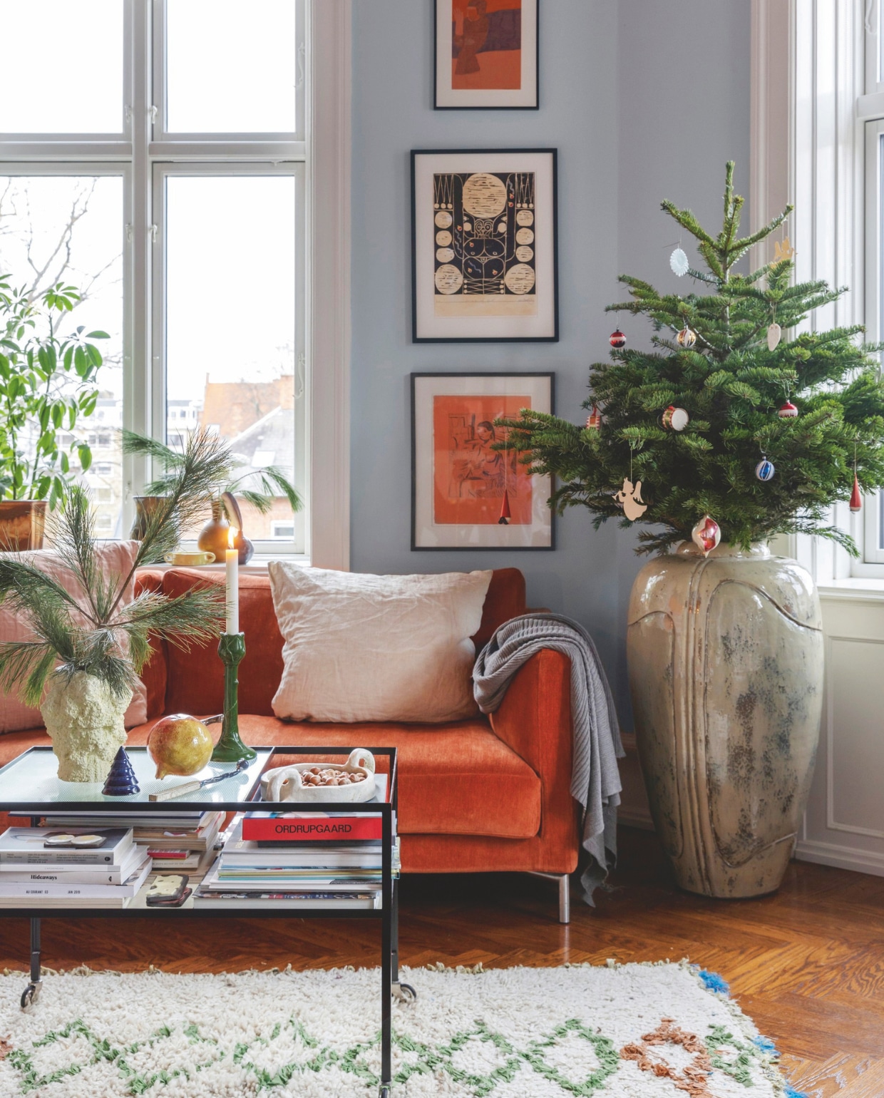 Bank Eilersen, kussens en plaid Stilleben, grote keramische pot Christian Bruun gekocht op Arts and Crafts Market Kopenhagen, salontafel Please Wait To Be Seated, Marokkaans vloerkleed By Fribert, kunst van Jan Oksbøll Callesen, Alexander Tovborg en Tal R. vtwonen 12-2024 | styling rikke graff juel | fotografie christina kayser