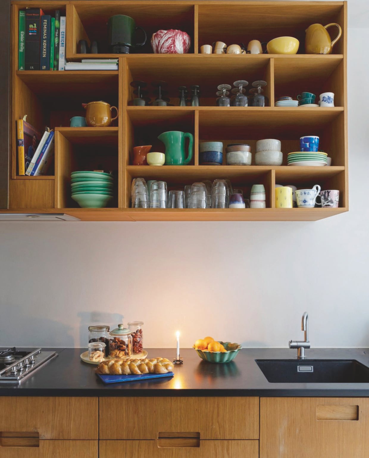 De eikenhouten keuken met werkblad van zwart natuursteen is maatwerk van Studio Flemming Lindholdt. Serviesgoed een mix van de Ursula serie van Royal Copenhagen, schalen van pottenbakker Mette Seedorff, vakantiesouvenirs en erfstukken. vtwonen 12-2024 | styling Rikke Graff Juel | fotografie Christina Kayser