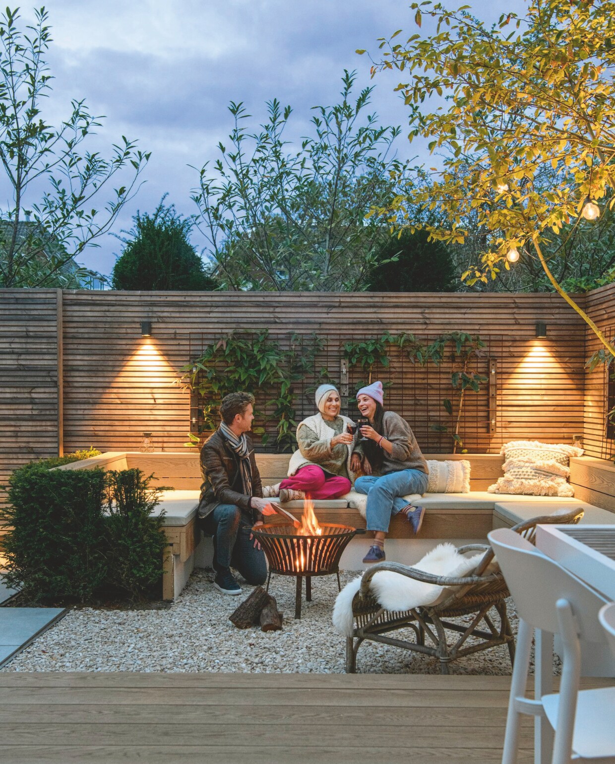 Zitbank op maat gemaakt, rieten stoel ByDennis, kussens H&amp;M Home, schapenvacht Volero, vuurkorf Karwei, tuintafel en -stoelen Kees Smit Tuinmeubelen. vtwonen 12-2024 | styling Marit Saladini | fotografie Louis Lemaire