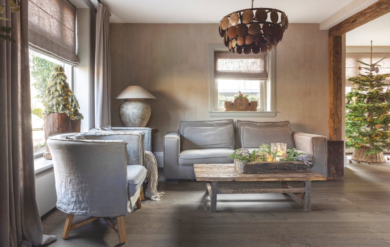 Bank, fauteuils en hanglamp van Hoffz, die laatste kocht Sabina bij Frieda Dorresteijn, net als de vouw-gordijnen. Salontafel van Landelijk en Sober Wonen. De kruiklamp komt van Met Landelijk Label. De eikenhouten balken leverde Frank Pouwers Historische Bouwmaterialen. Eikenhouten vloer van ’t Achterhuis. Het kerstgroen haalde Sabina bij Tuincentrum Global Garden. vtwonen landelijk 07-2024 | fotografie Anneke Gambon