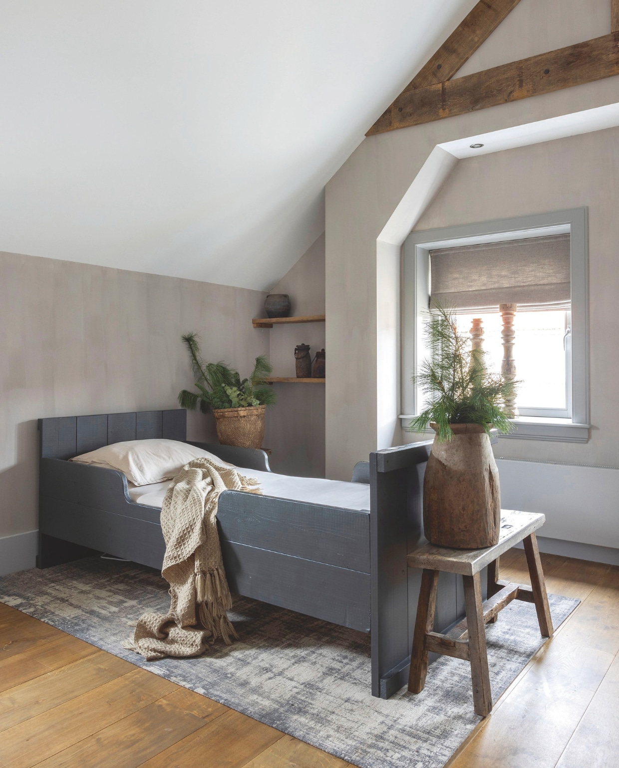 Het bed is gemaakt van steigerhout en geverfd in kleur ON0021 van Sikkens. Het kleed is van Karwei, het lampje van Frieda Dorresteijn. Voor het bed staat een bankje van Landelijk en Sober wonen. De pot en de kandelaren in de vensterbank zijn gekocht bij Rust &amp; tiek. vtwonen landelijk 07-2024 | fotografie Anneke Gambon