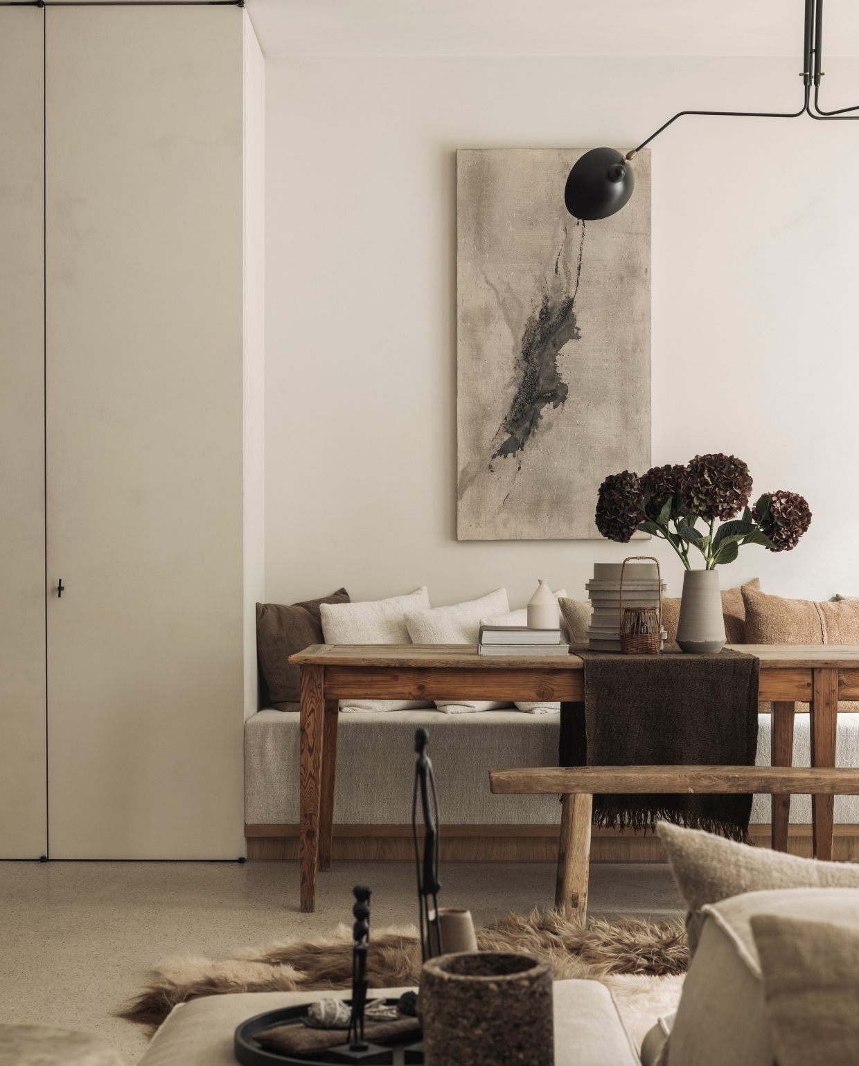 Eettafel komt van een vlooienmarkt in Barcelona. Lamp van Serge Mouille. Het kunstwerk aan de muur is van Eleanor Herbosch. De kast is maatwerk evenals de bank. De houten bank komt van The Corner Studio. Loungebank en poef Extrasoft van Living Divani met kussens van Isabelle Yamamoto. stijlvol wonen 01-2025 | fotografie Tijs Vervecken