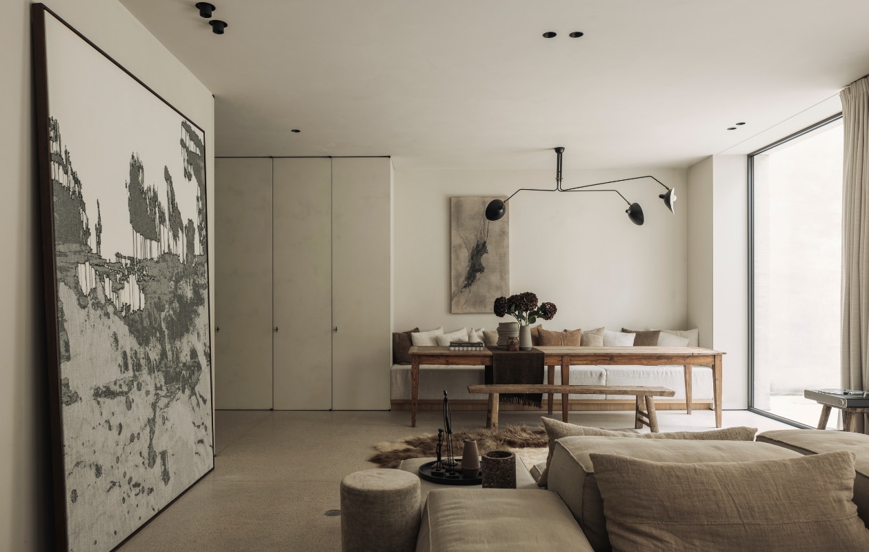 Eettafel van een vlooienmarkt in Barcelona. Lamp van Serge Mouille. Het kunstwerk aan de muur is van Eleanor Herbosch. Kunstwerk links Nathalie Van der Massen. De kast is maatwerk evenals de bank bij de eettafel. De houten bank komt van The Corner Studio. Loungebank en poef Extrasoft van Living Divani met kussens van Isabelle Yamamoto. Vacht van Carine Boxy. stijlvol wonen 01-2025 | fotografie Tijs Vervecken