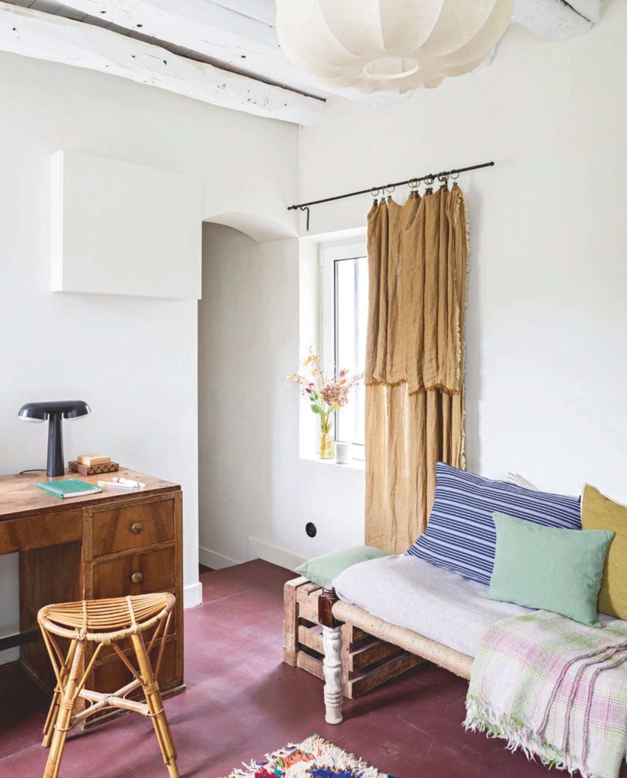 Gepolijste betonvloer in de kleur Garnet, Mercadier. Bureau en kruk Selency, gordijnen Le Monde Sauvage, Marokkaans kleed Leboncoin, plafondlamp La Lune Décoration. vtwonen 13-2024 | styling Marie-Maud Levron | fotografie Yann Deret
