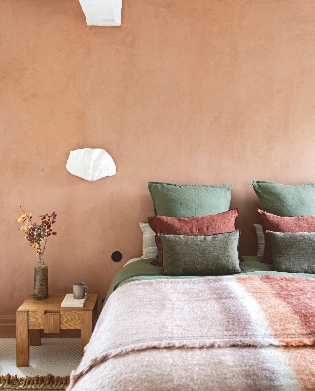 Antiek nachtkastje, schelplamp Axel Chay. Beddengoed en deken Le Monde Sauvage, kussens Maisons du Monde. vtwonen 13-2024 | styling Marie-Maud Levron | fotografie Yann Deret