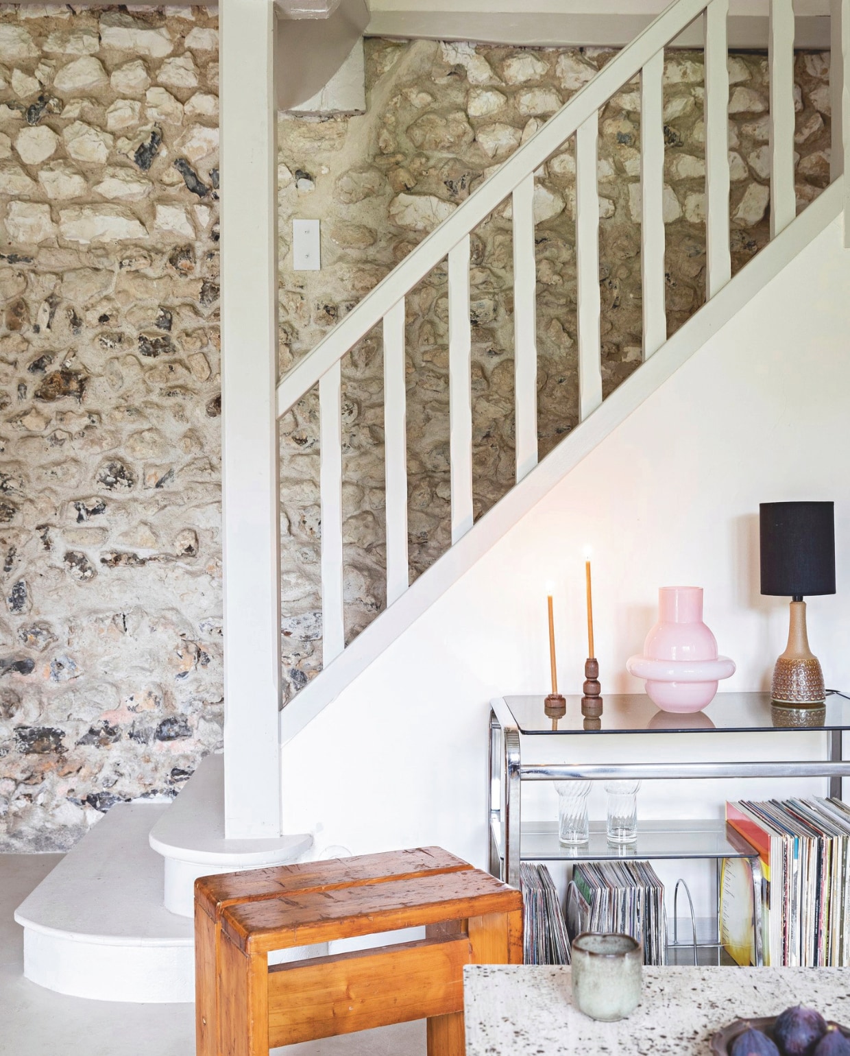 Vloer gepolijst beton Mercadier, kleed Am-PM via La Redoute. Salontafel DIY van een stuk travertijn. Houten kruk van Charlotte Perriand en trolley via Selency. vtwonen 13-2024 | styling Marie-Maud Levron | fotografie Yann Deret