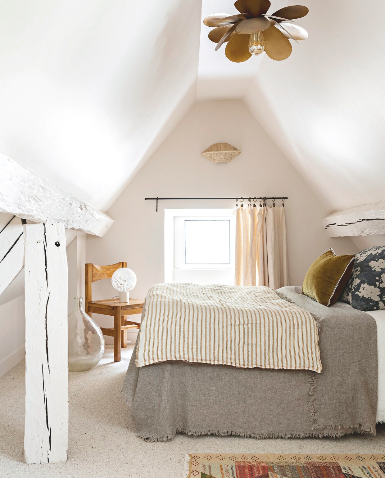 Witte verf op balken: vergelijkbaar Wood Ash van Little Greene. Wollen deken Maison de Vacances, dekbed Tensira, oker kussens Elitis, bloemenkussen Le Monde Sauvage. Kleed Caravane, houten stoel La Lune-decoratie. Bedlamp van Margaux Keller, gordijn Le Monde Sauvage, wandlamp Socialite Family. vtwonen 13-2024 | styling Marie-Maud Levron | fotografie Yann Deret