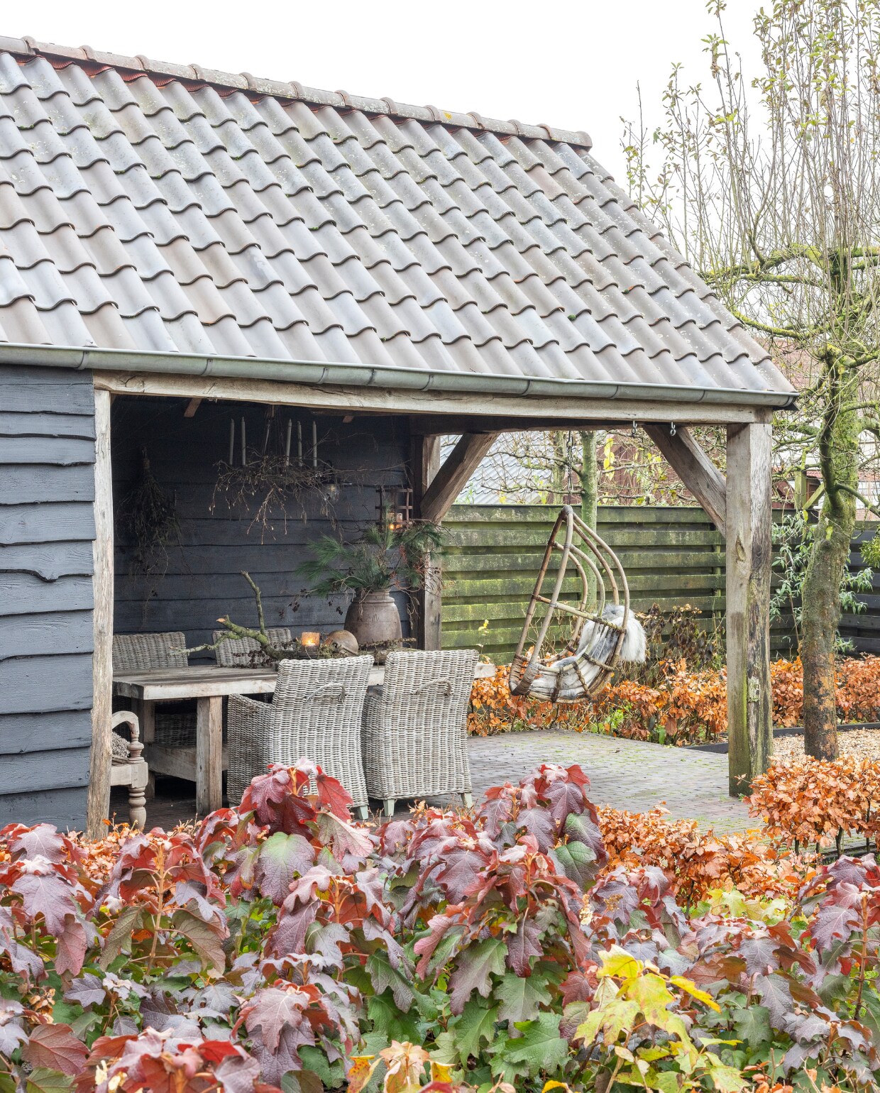 Ook buiten doet mee met kerst. Onder de veranda hangt een kaarsenluchter en de tafel is gestyled met accessoires van Bibi’s Lifestyle. vtwonen landelijk 07-2024 | Fotografie Anneke Gambon