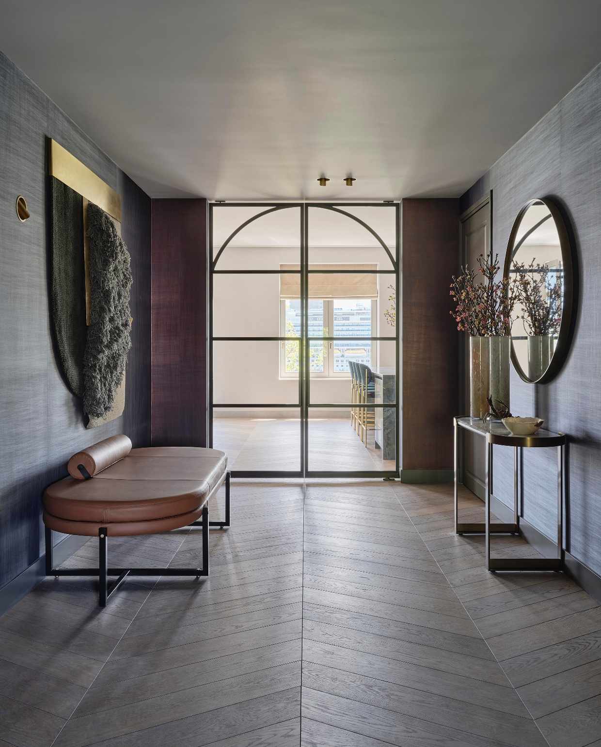 Aan de muur in de ruime hal hangt een wandkleed van CC-tapis. In de stalen deuren zit een ronding die de bogen uit het oude gebouw terughaalt. Bank Arflex, spiegel Sovet, sidetable Eichholtz. stijlvol wonen 08-2024 | fotografie Space Content Studio